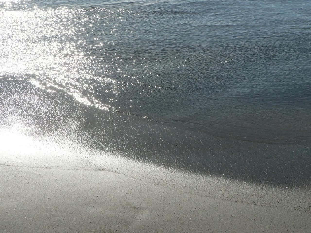 Beach Sand 桌布 壁紙 — 陽光在輕柔的海浪上舞動，拍打著淡沙色的海岸。