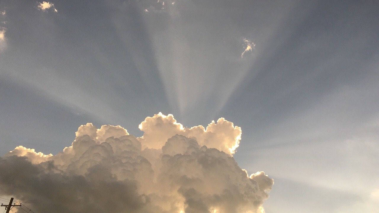Light 桌布 壁紙 — 陽光戲劇性地穿透高聳的積雲，映襯著柔和的藍天。