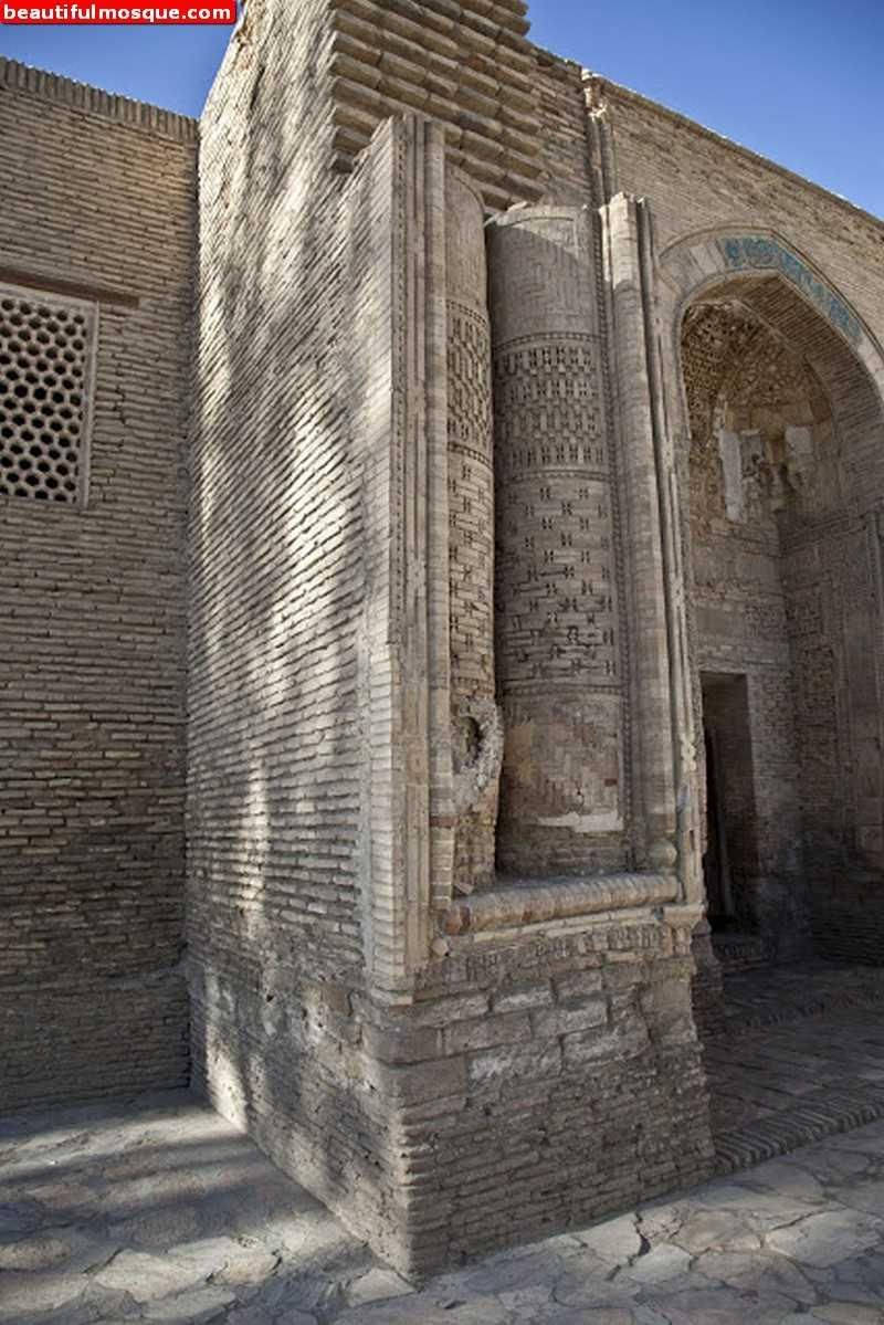 Uzbekistan 桌布 壁紙 — 陽光普照的古老磚砌清真寺，帶有複雜的幾何圖案和拱形門口，襯托著清澈的藍天。