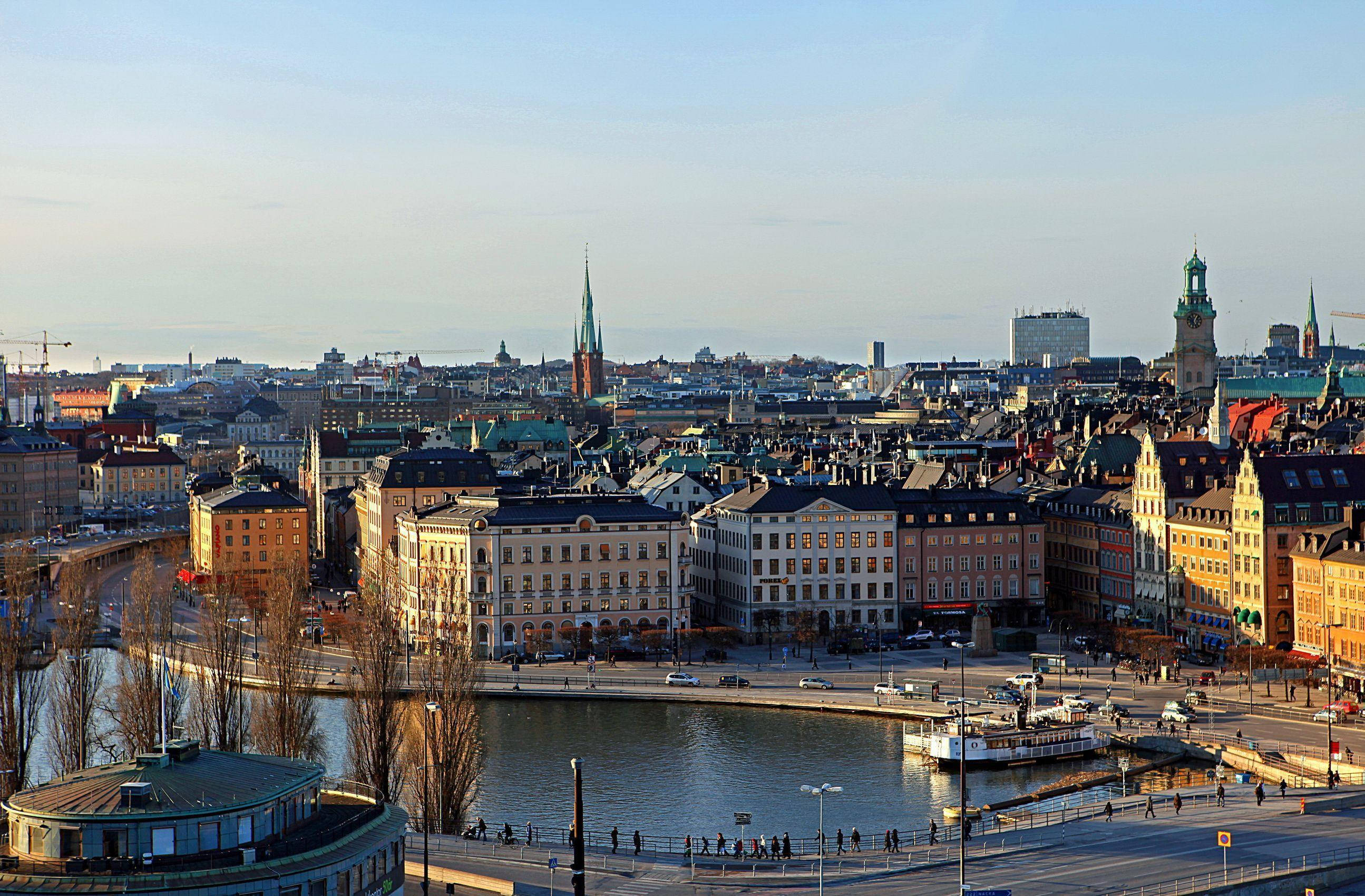 Sweden 桌布 壁紙 — 陽光普照的斯德哥爾摩城市景觀，河畔歷史建築與教堂尖塔刺破清澈藍天。