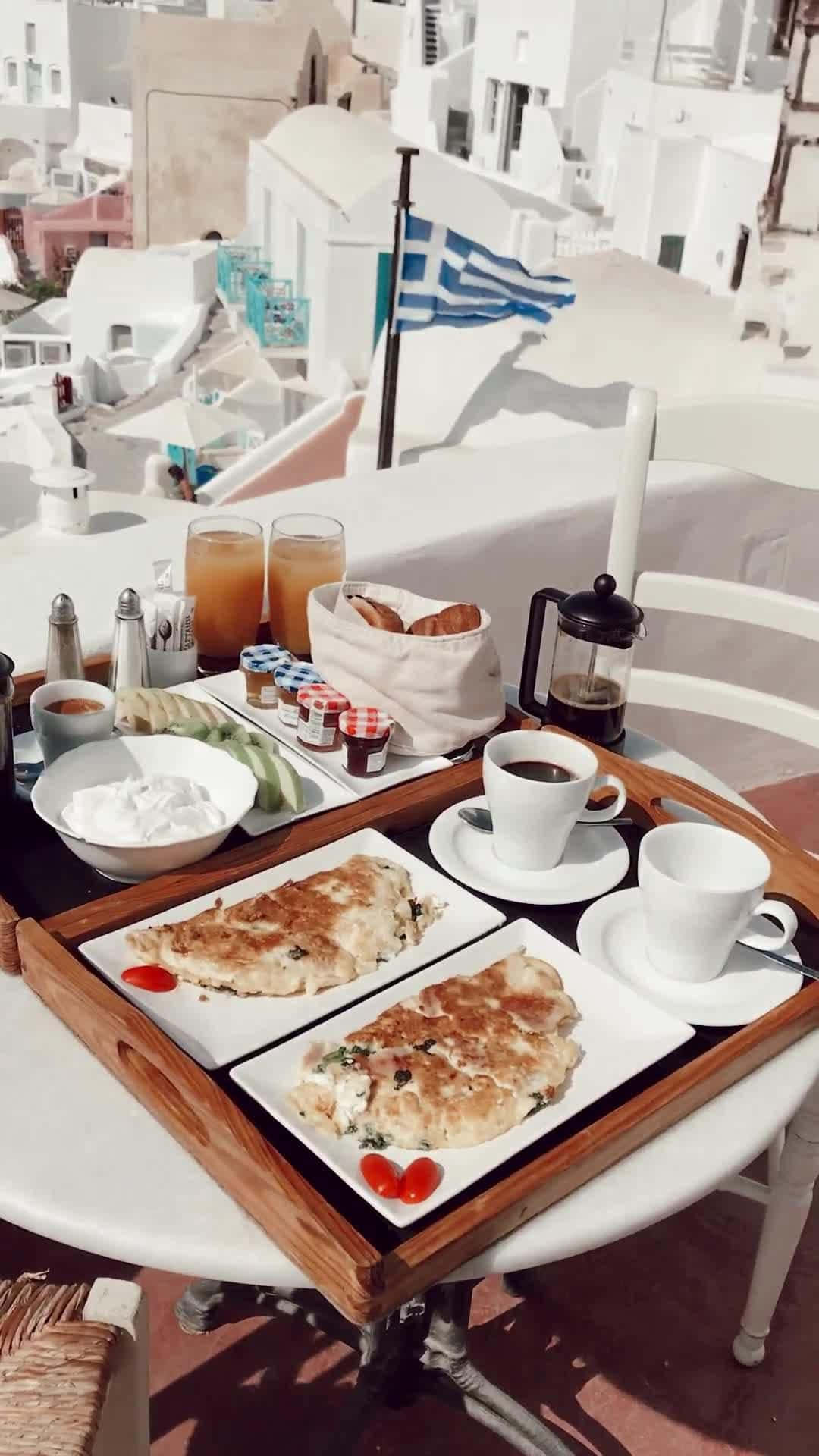 Travelling 桌布 壁紙 — 陽光普照的早餐托盤上有蛋捲、咖啡和希臘美食，俯瞰著粉刷成白色的建築物和飄揚的希臘國旗。