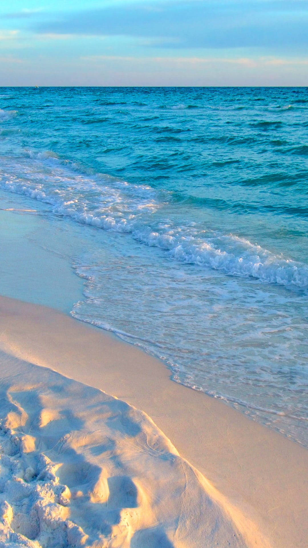Beach Phone 桌布 壁紙 — 陽光普照的碧綠海浪輕輕拍打著純淨的白色沙灘，天空柔和湛藍。