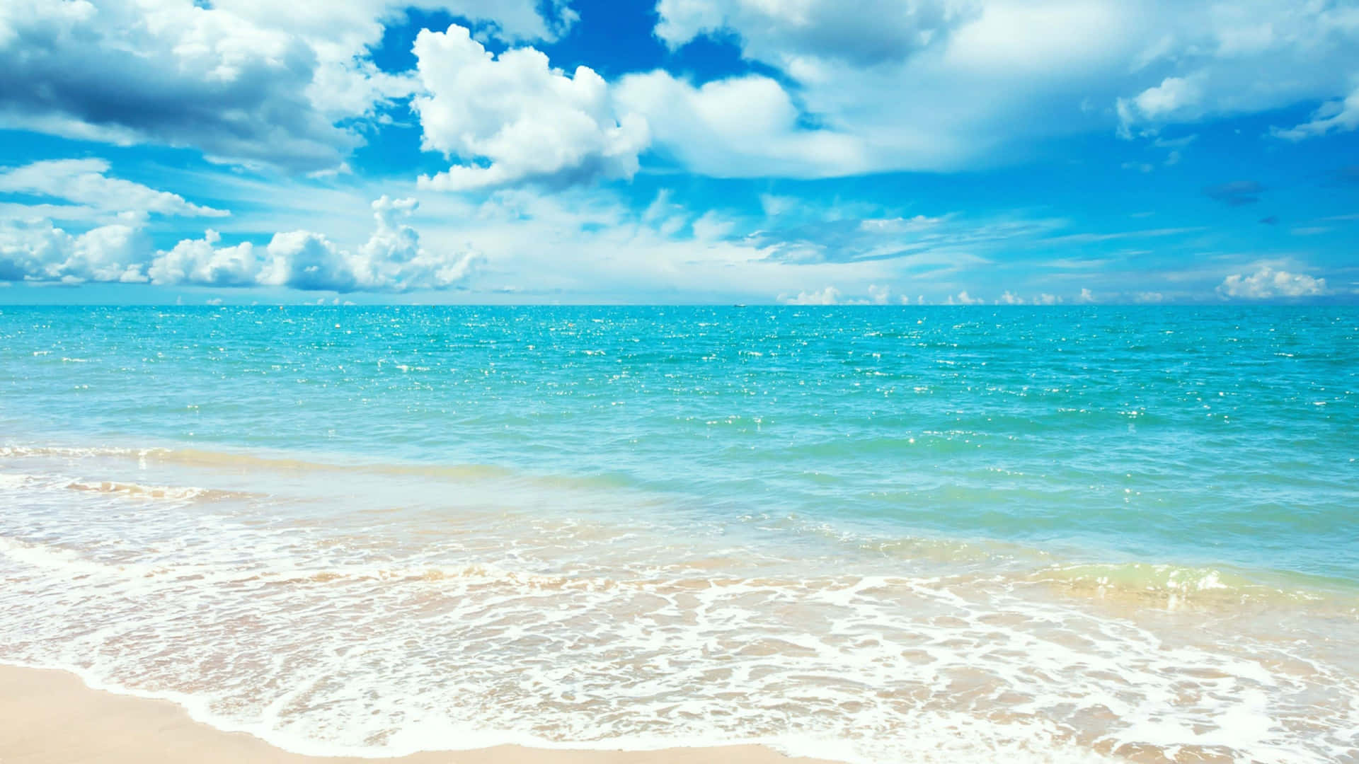 Summer Zoom 桌布 壁紙 — 陽光普照的碧綠海浪輕輕拍打著金色沙灘，上方是點綴著蓬鬆白雲的湛藍天空。