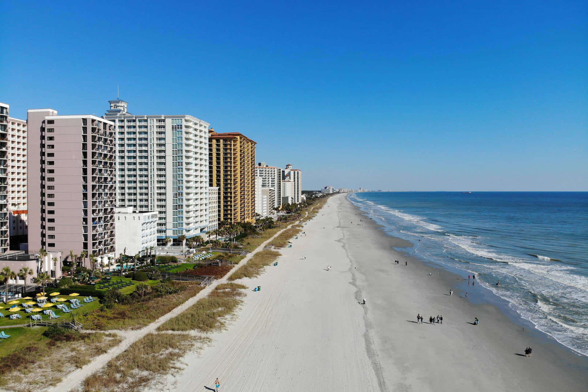 Myrtle Beach 桌布 壁紙 — 陽光海灘的鳥瞰圖，高聳的飯店沿著海岸排列，人們享受沙灘和海浪。