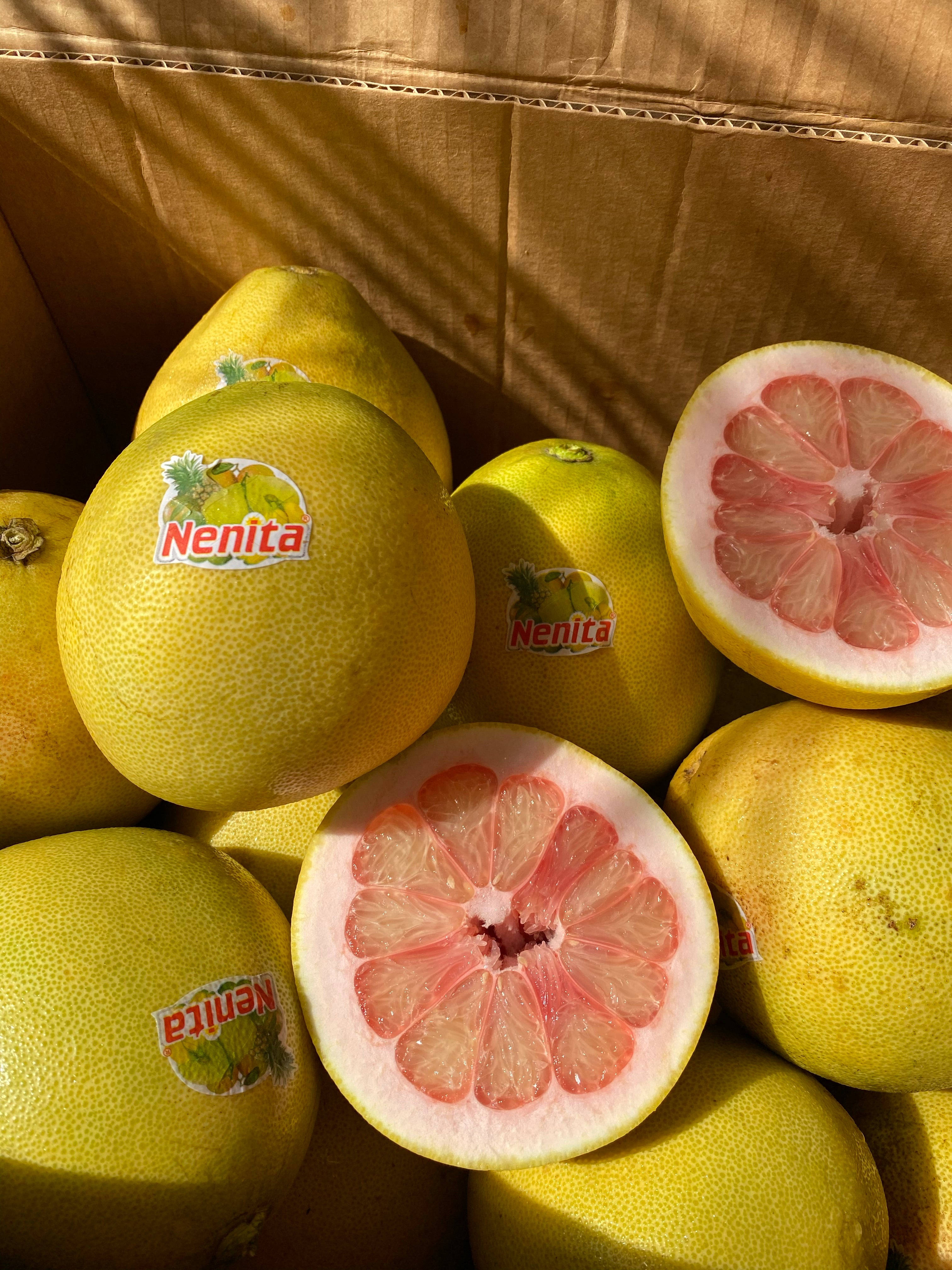 Fruits 桌布 壁紙 — 陽光照射下的Nenita品牌葡萄柚盒，兩半露出多汁的粉紅色果肉。
