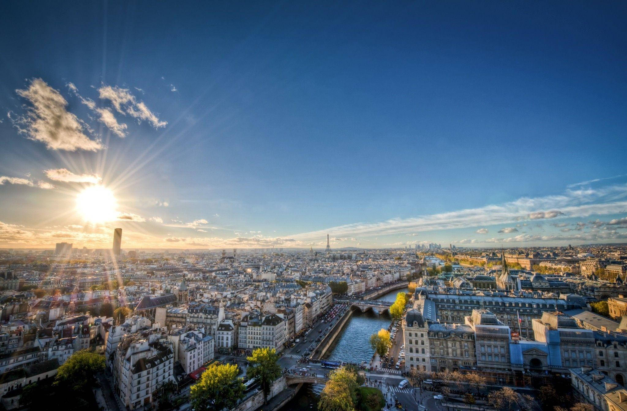 Europe 桌布 壁紙 — 陽光照射巴黎天際線，艾菲爾鐵塔和塞納河蜿蜒穿過歷史屋頂。
