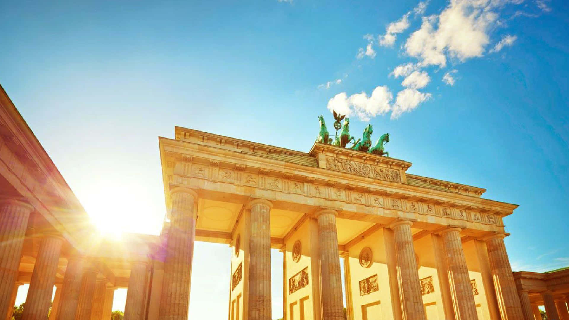 Blue Sky 桌布 壁紙 — 陽光照射著新古典主義的布蘭登堡門，天空湛藍，雲朵點綴。