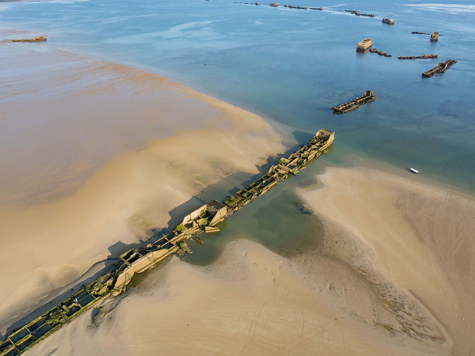 French Beach 桌布 壁紙 — 陽光照耀下的沉船擱淺在沙灘和淺藍綠色水域的鳥瞰圖。