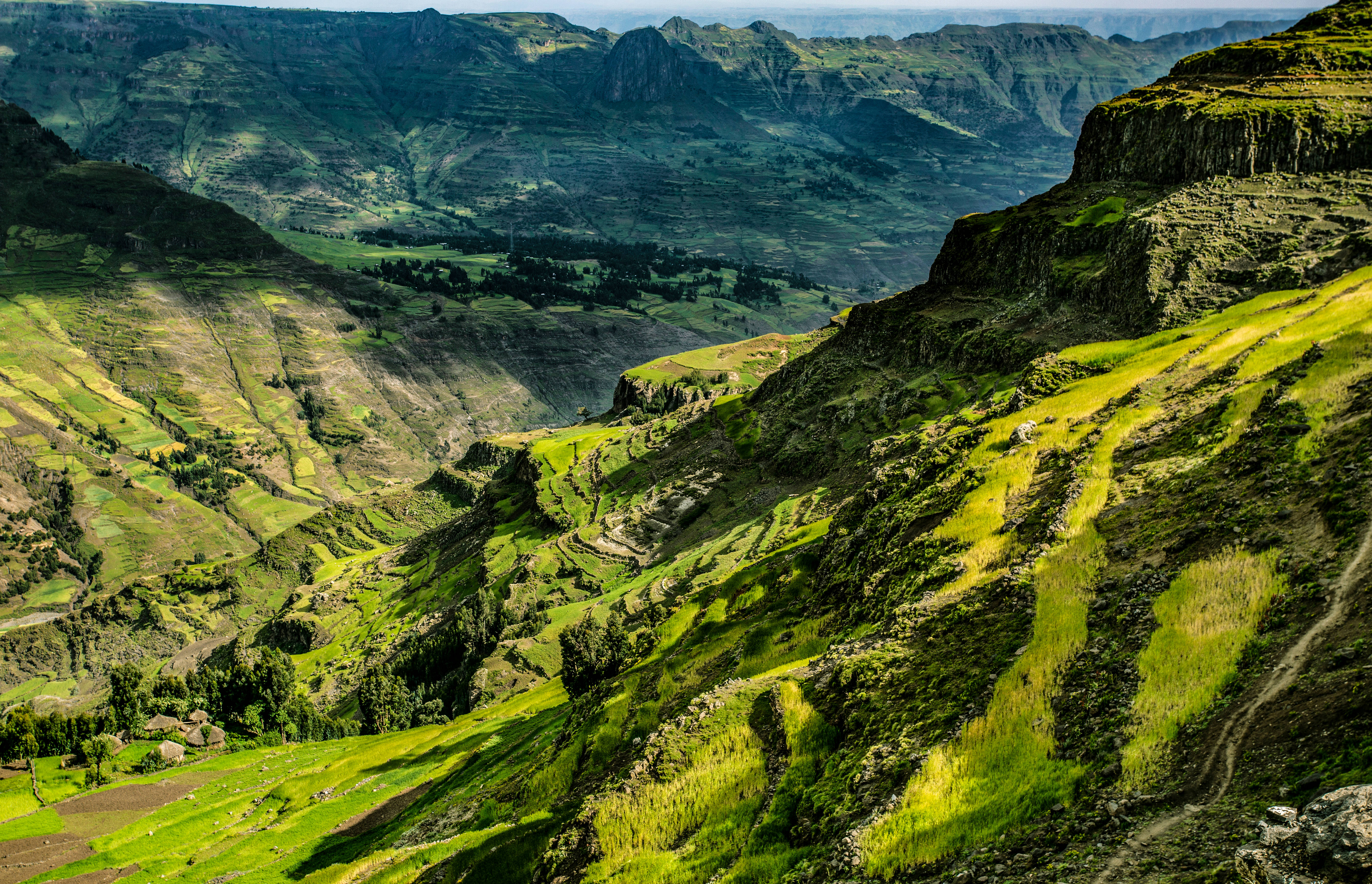 Ethiopia 桌布 壁紙 — 陽光照耀下的綠色山谷和崎嶇的山脊在晴朗的天空下延伸至遠方。