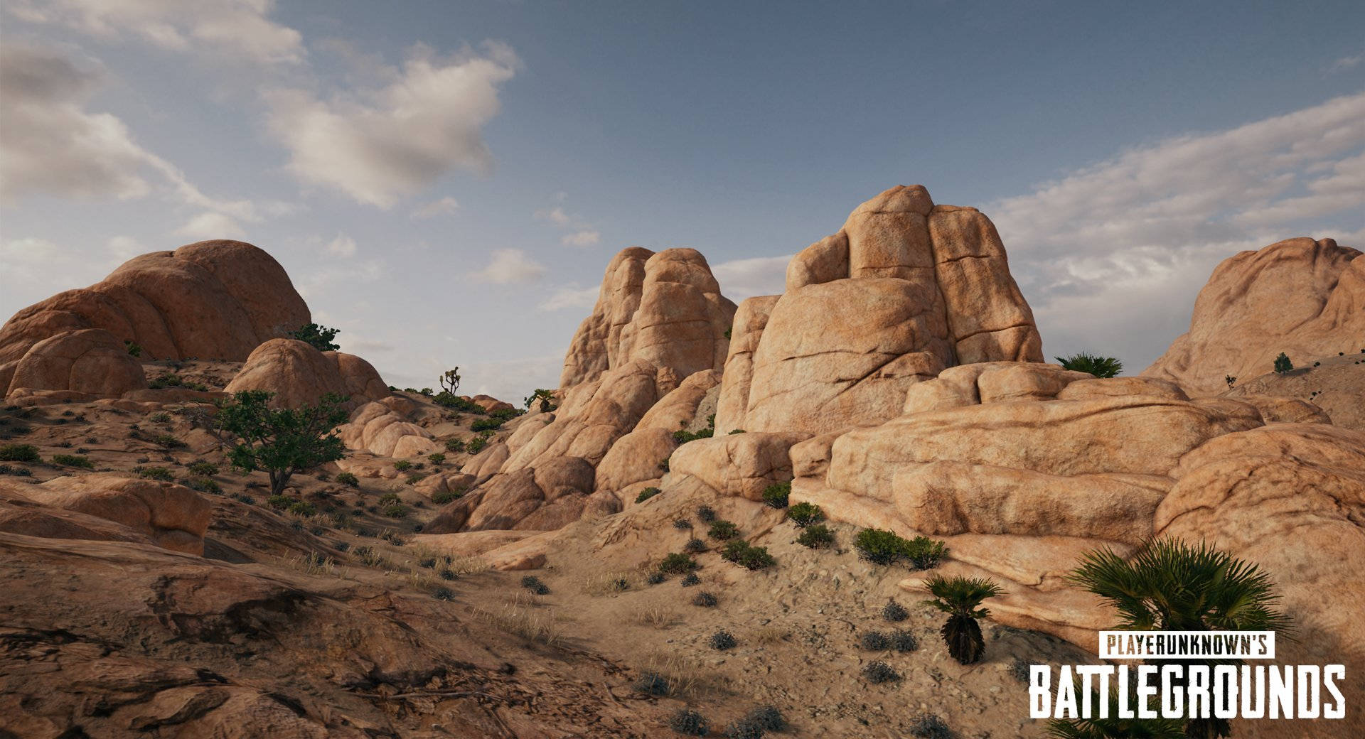 藍天下有大型岩層和稀疏植被的沙漠地形。 — PUBG 4K 壁紙 壁紙