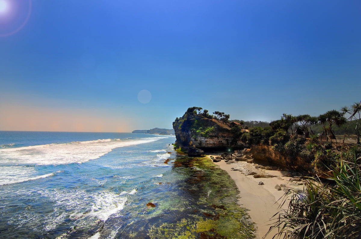 Tropical Beach 桌布 壁紙 — 陽光照耀的海岸懸崖，碧綠色的海浪拍打著沙灘，天空清澈湛藍。