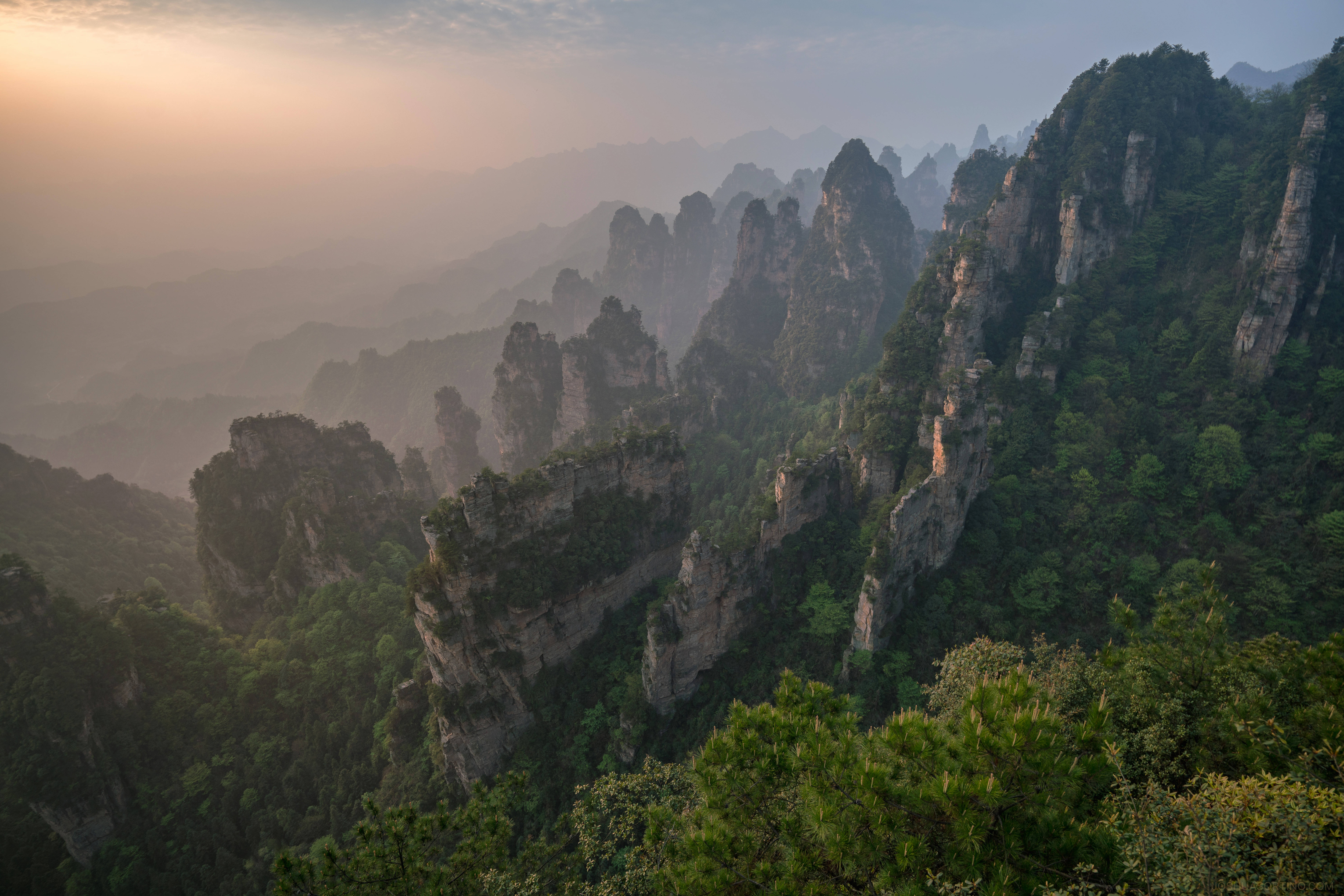 山脈 桌布 壁紙 — 陽光照耀著從寧靜山谷中茂密綠色森林升起的霧氣繚繞的花崗岩尖峰。