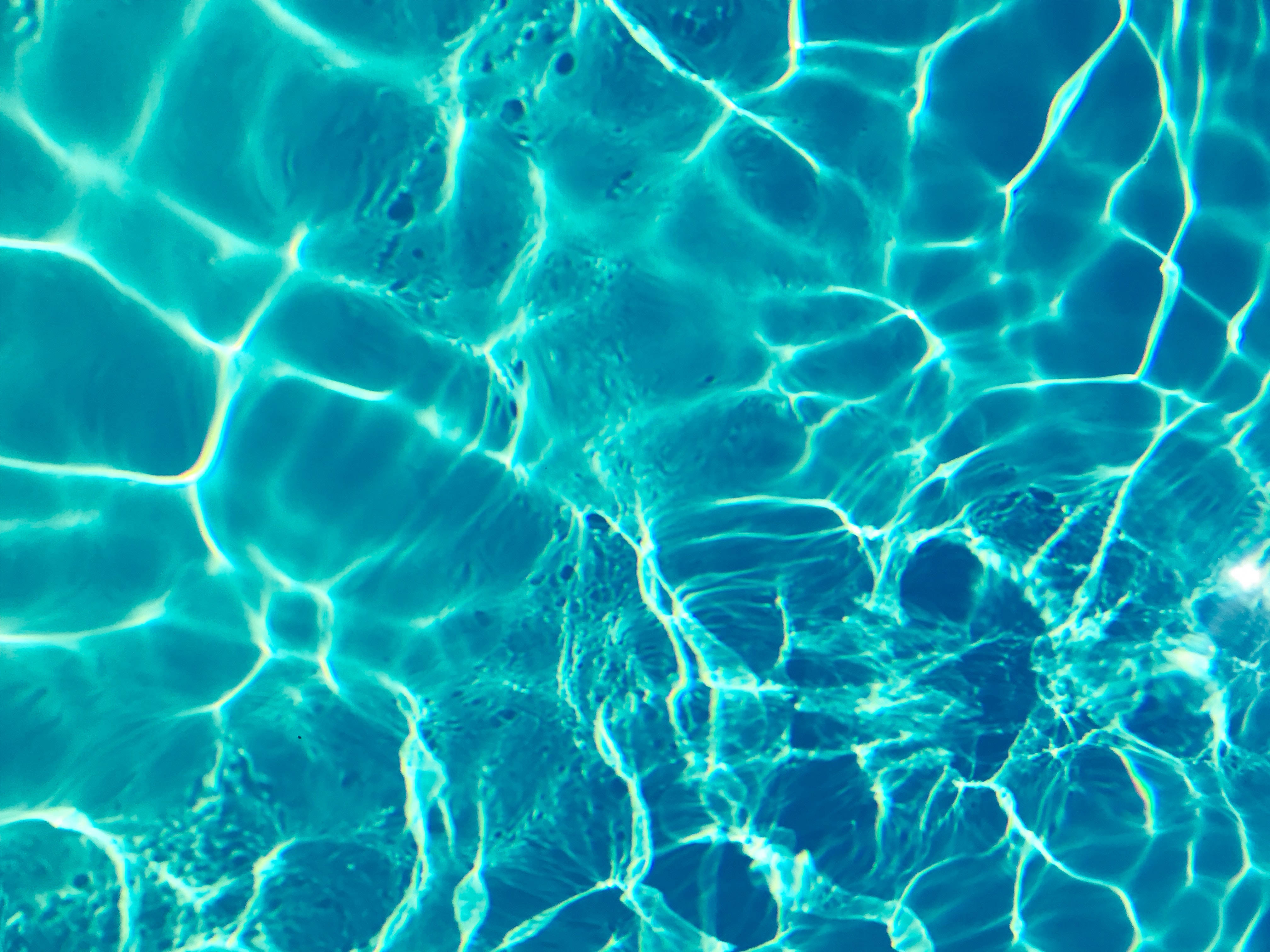 Swimming 桌布 壁紙 — 陽光碎裂成發光的綠松石圖案，在漣漪的泳池水面上閃爍。
