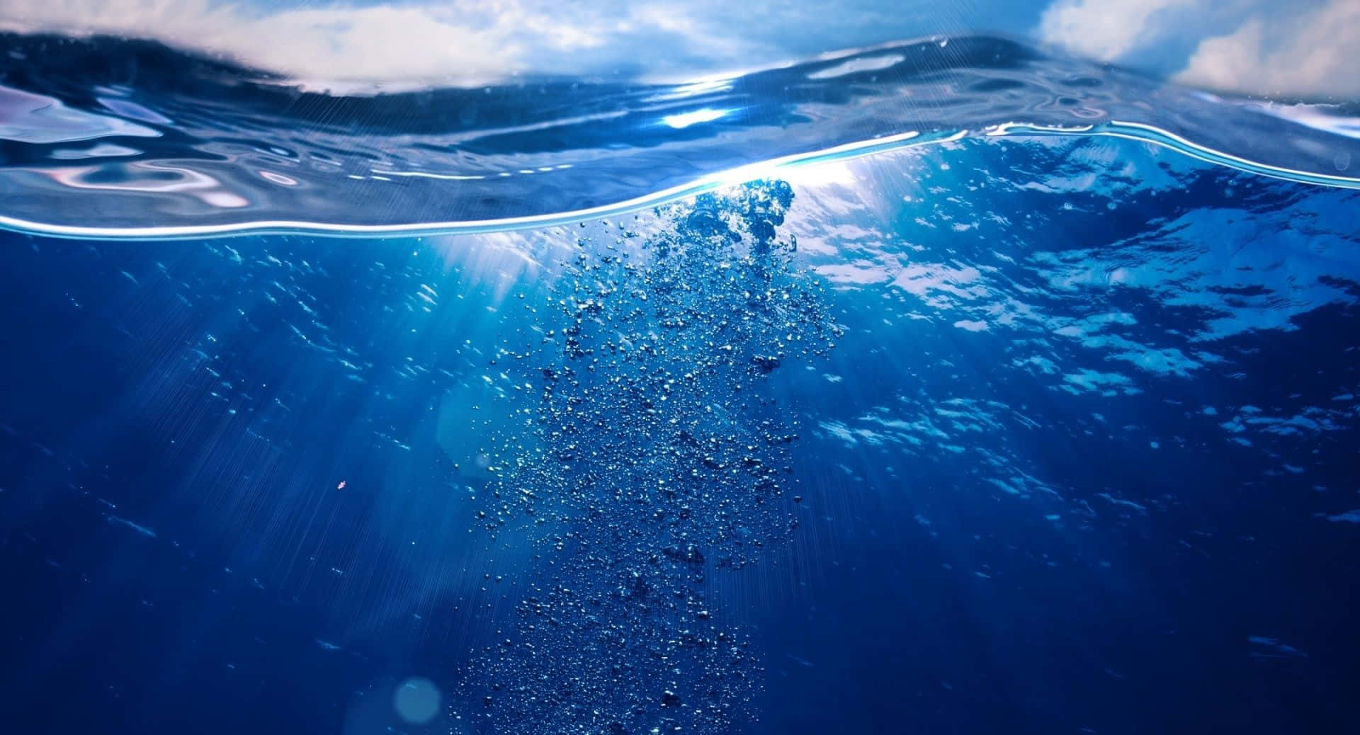 水 桌布 壁紙 — 陽光穿透海面，在深藍色海水中透過上升的氣泡投射出光線。