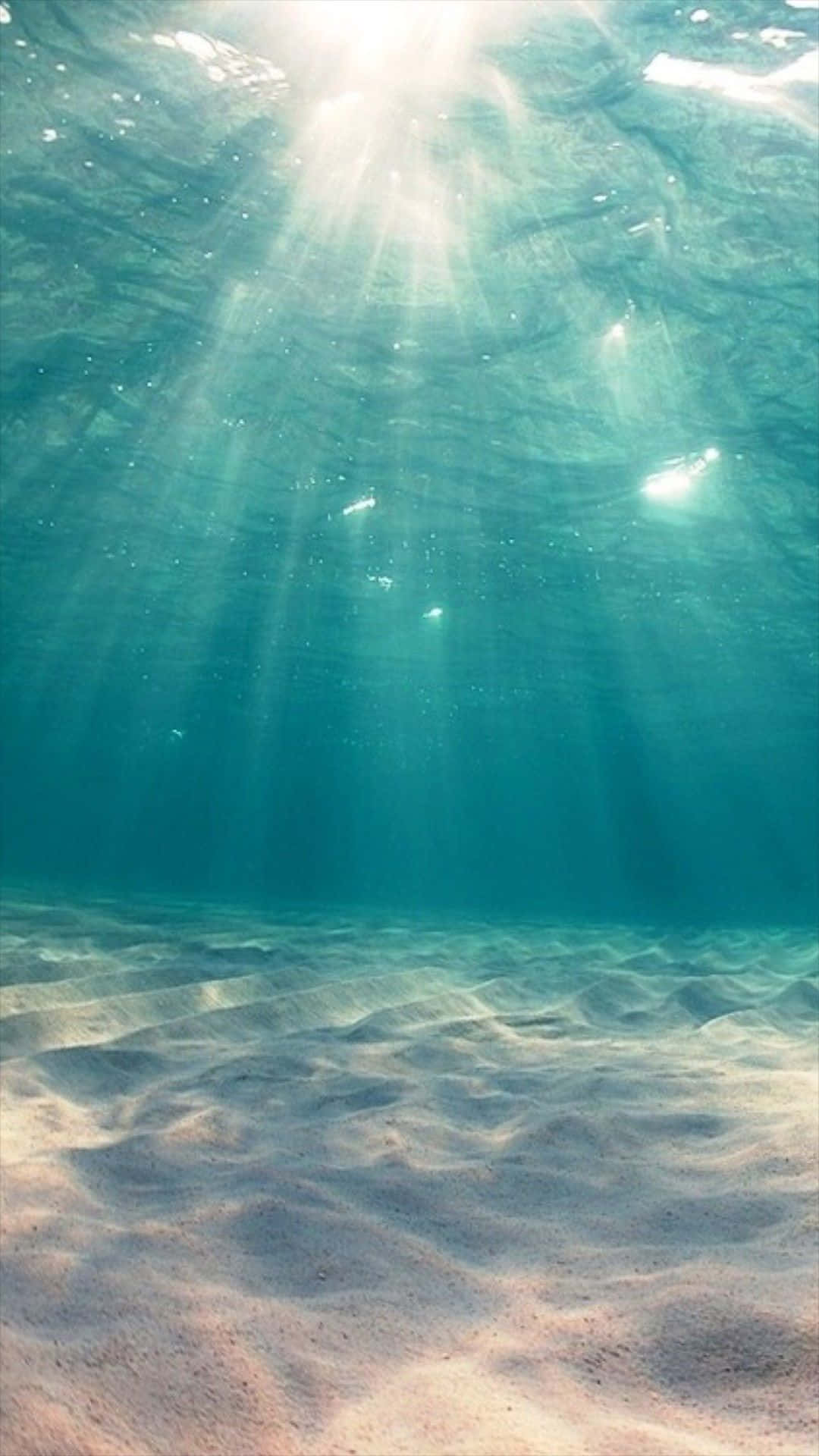 Cyan Aesthetic 桌布 壁紙 — 陽光穿透碧綠海水，將空靈光線投射在波紋狀的沙質海床上。