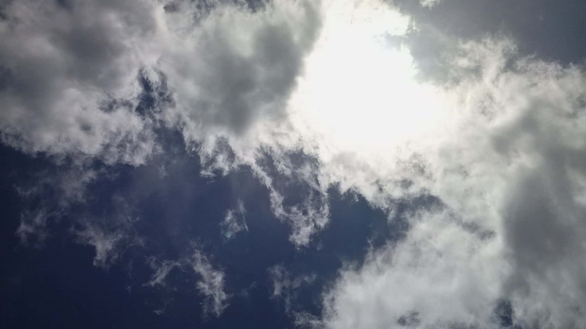 CLOUD-17 壁紙 — 陽光穿透縷縷白雲，映襯著深藍色的天空，營造出戲劇性的自然景象。