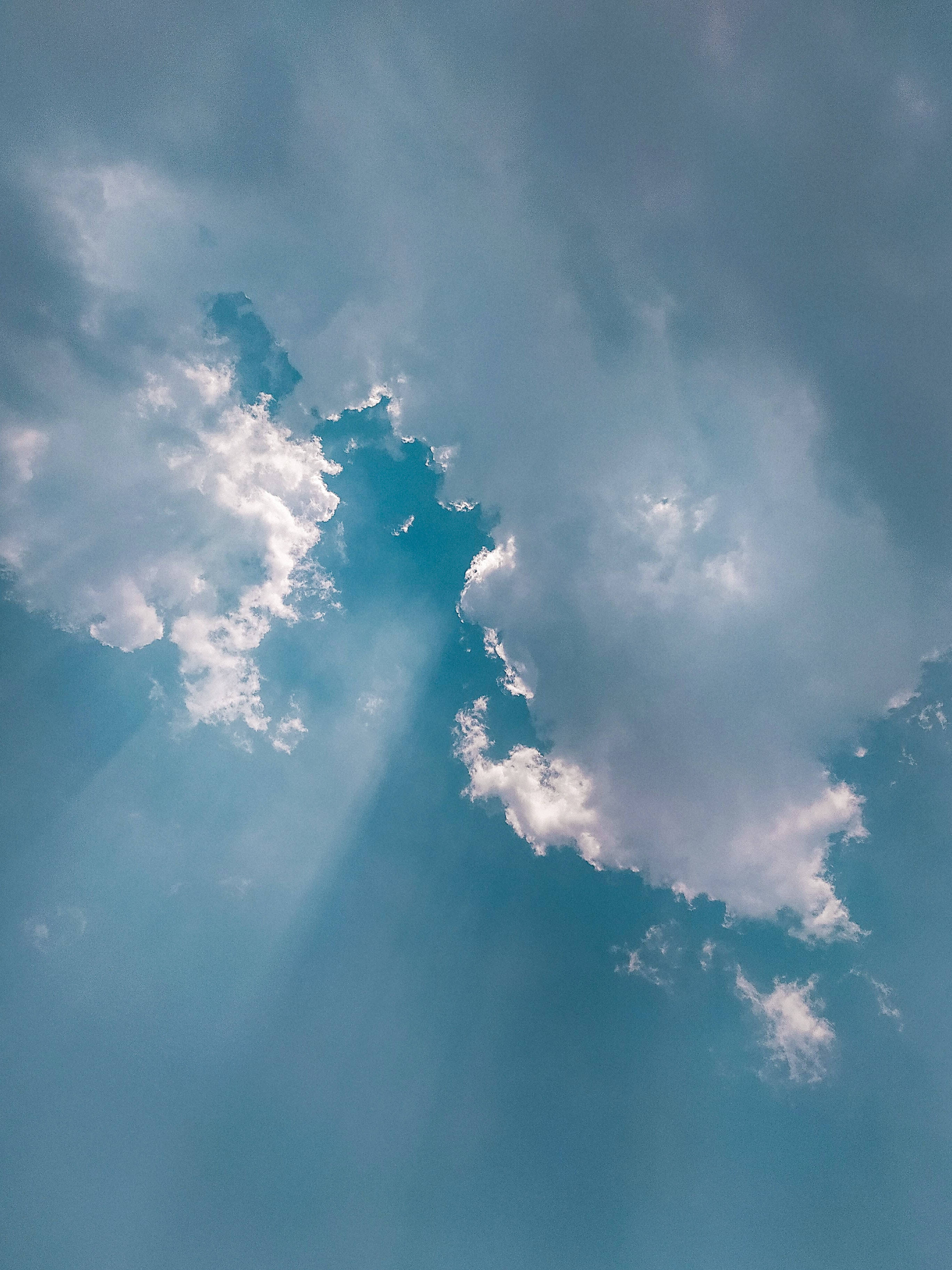 雲朵 桌布 壁紙 — 陽光穿透蓬鬆的白雲，映照在寧靜的藍天上。