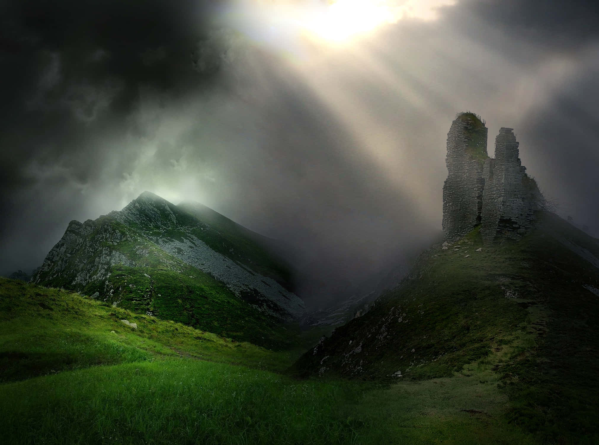 Ireland Desktop 桌布 壁紙 — 陽光穿透黑暗的暴風雲，照亮長滿苔蘚的山脈和古老的石頭廢墟。
