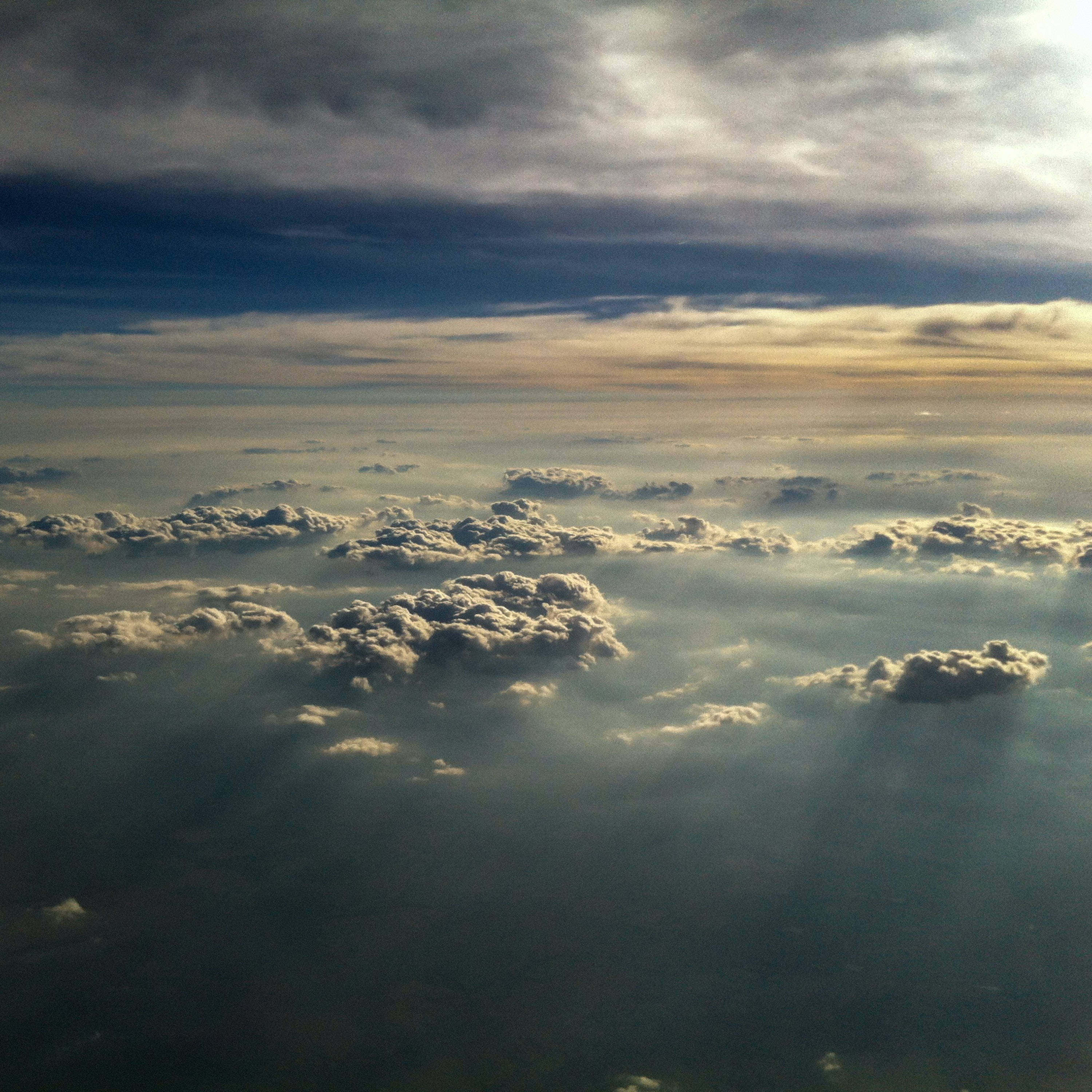 Beautiful Sky 桌布 壁紙 — 陽光穿過層層雲層，在下方廣闊的海洋上投射出金色的光芒。