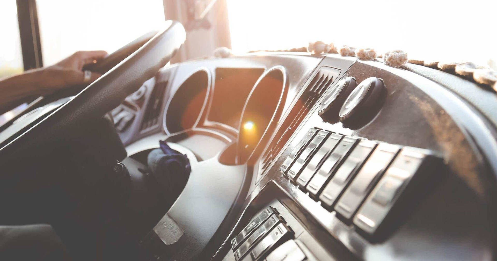 drive 桌布 壁紙 — 陽光穿過復古車的擋風玻璃，照亮了陳舊的儀表板和駕駛放在方向盤上的手。