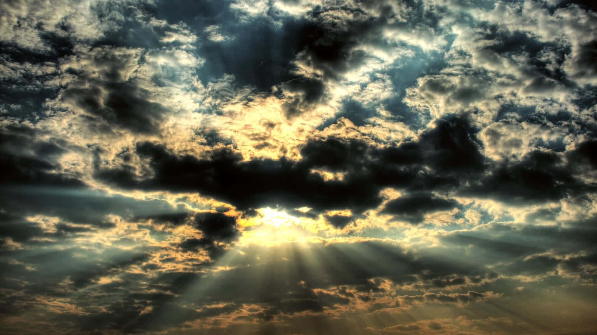 Clouds Aesthetics 桌布 壁紙 — 陽光穿過戲劇性的烏雲，在金色的日落天空中爆發。