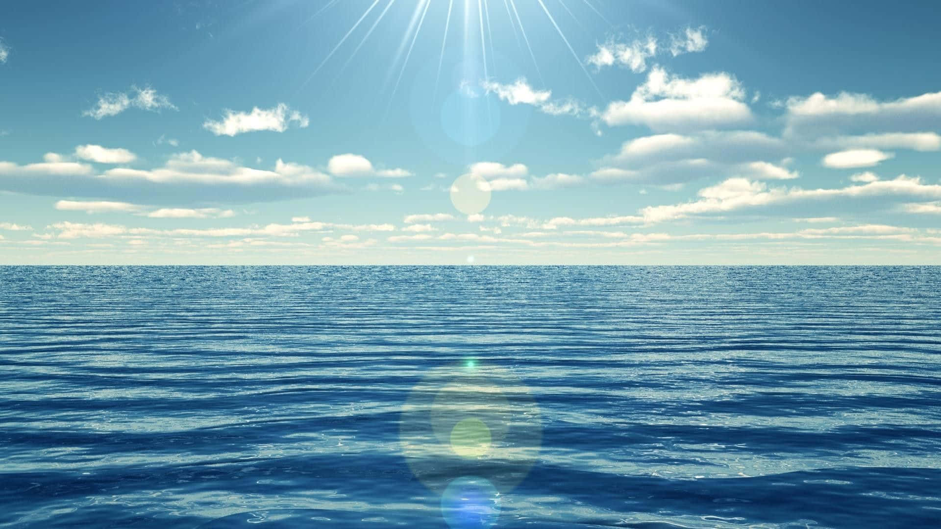 Relaxing 桌布 壁紙 — 陽光穿過散落的雲層，照耀在晴朗天空下一片廣闊平靜的藍色海洋上。
