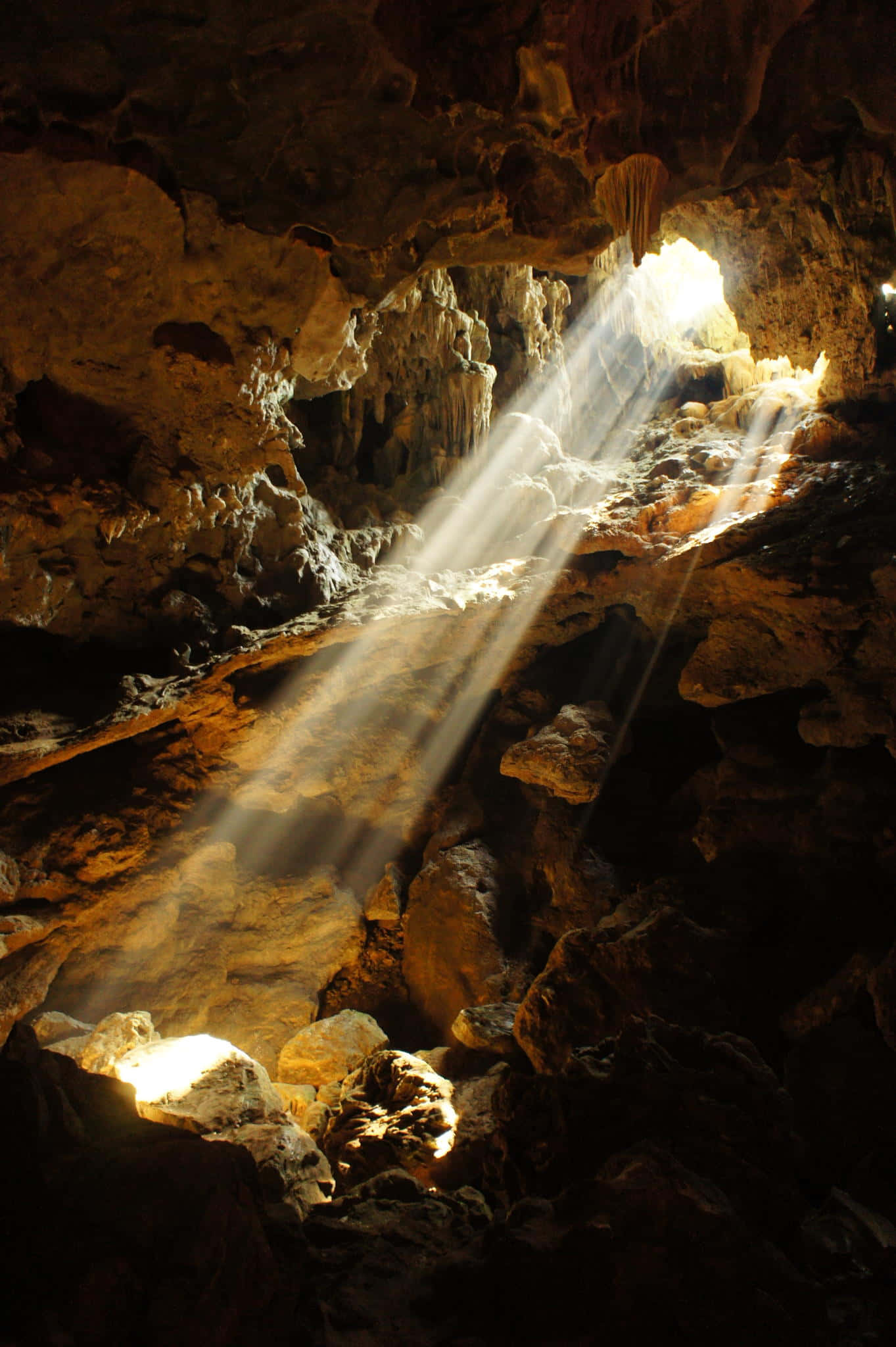 Cave 桌布 壁紙 — 陽光穿過洞穴入口，照亮崎嶇的岩石結構，投下戲劇性的陰影。