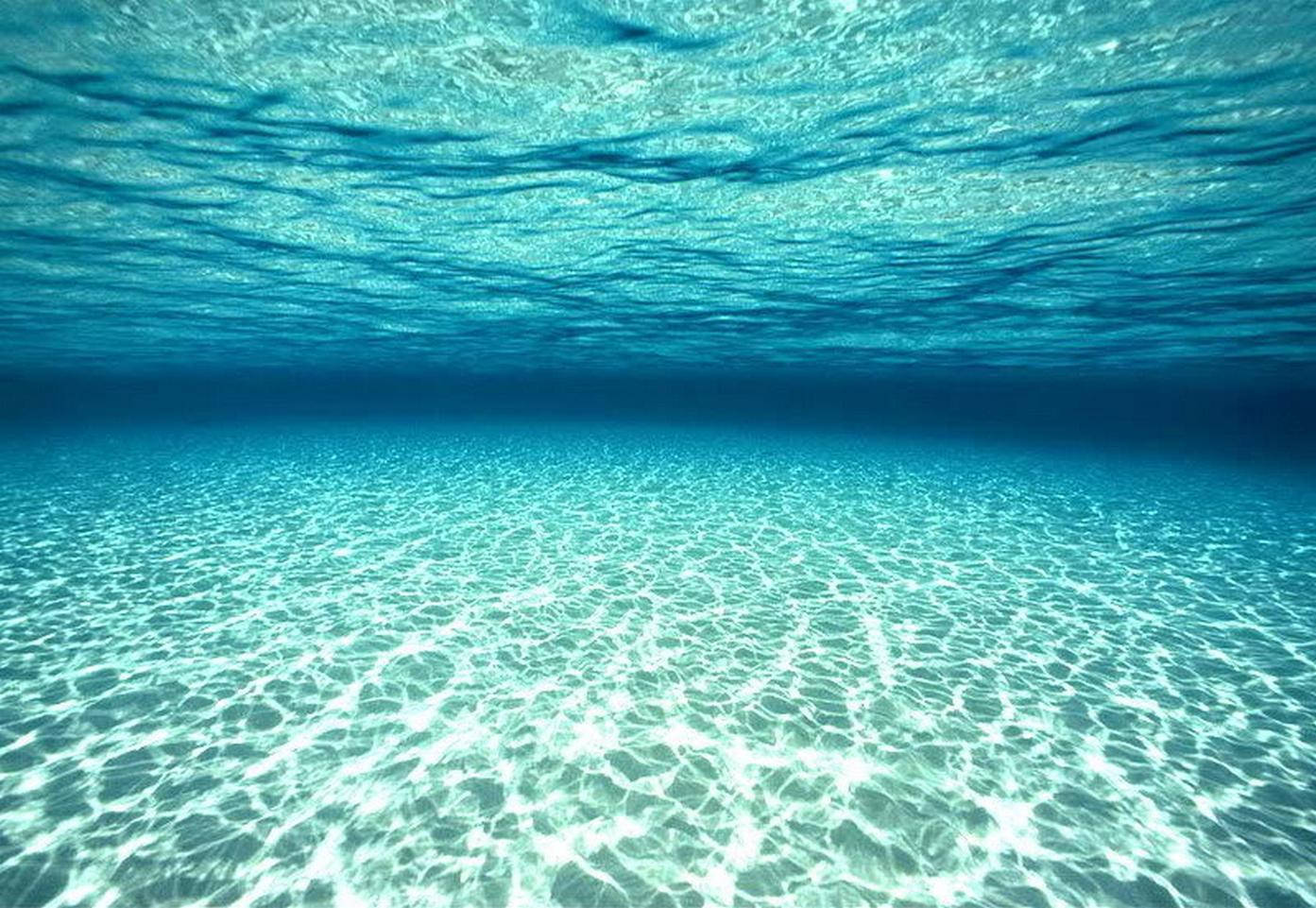 水下動畫 桌布 壁紙 — 陽光穿過清澈的碧綠海水，在沙質海底上舞動，形成閃爍的圖案。