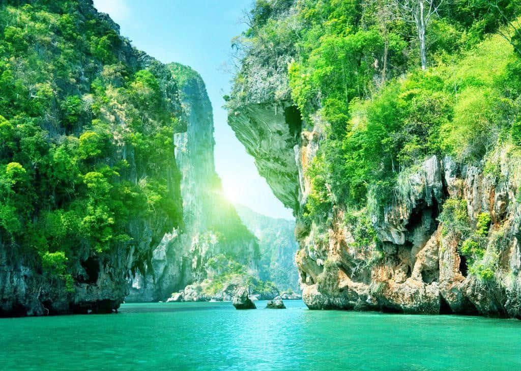 Beautiful Place 桌布 壁紙 — 陽光穿過狹窄的峽谷，兩旁是茂密的綠色懸崖，襯托著碧綠色的海水和小船。