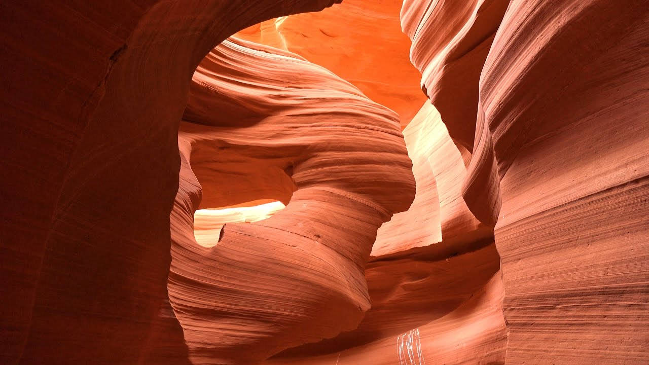 風景 桌布 壁紙 — 陽光穿過狹窄的狹縫峽谷，照亮了帶有光滑層狀紋理的旋轉紅色砂岩牆壁。