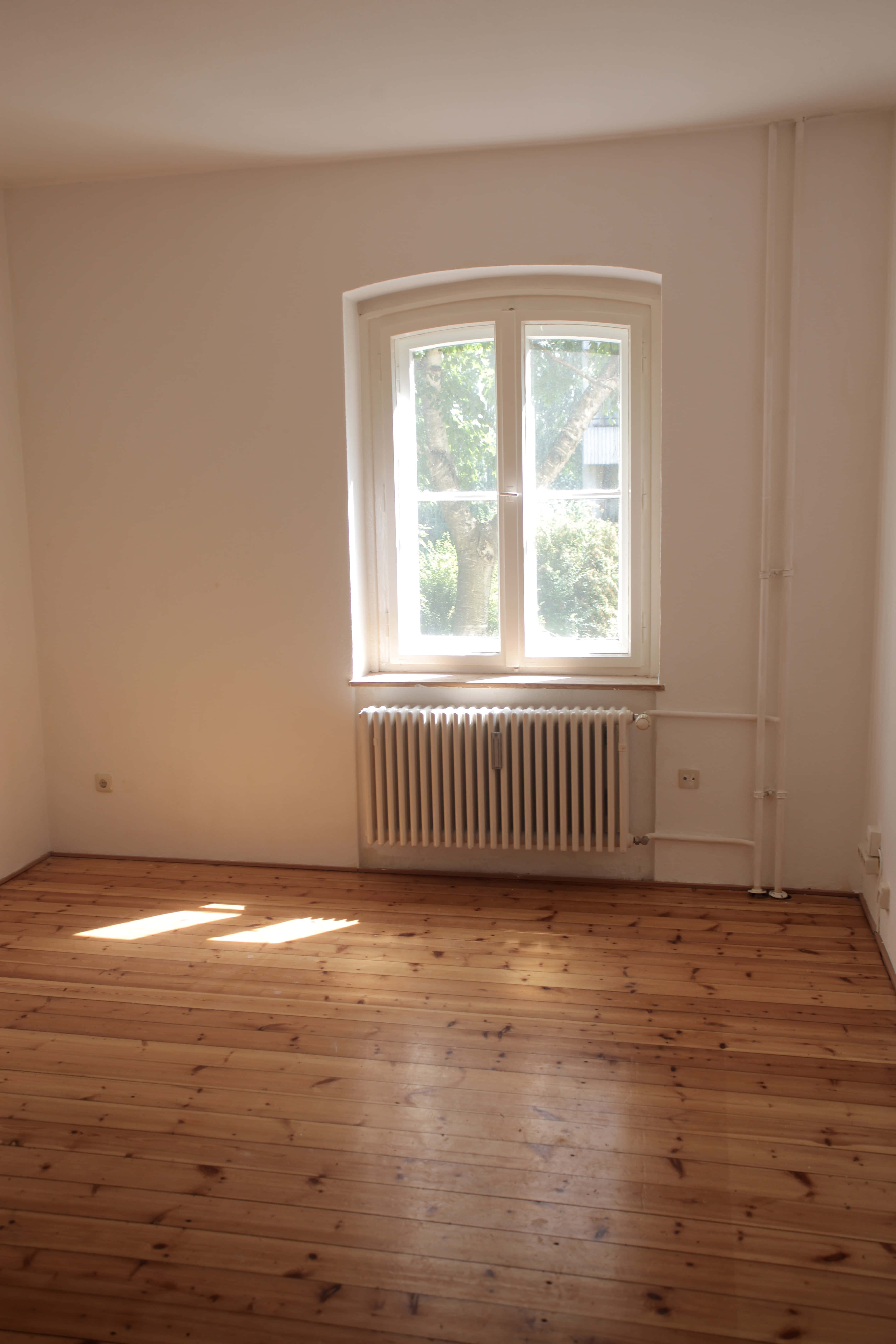 Empty Room 桌布 壁紙 — 陽光穿過白色拱形窗戶，灑在空無一物的極簡房間的溫暖木地板上。