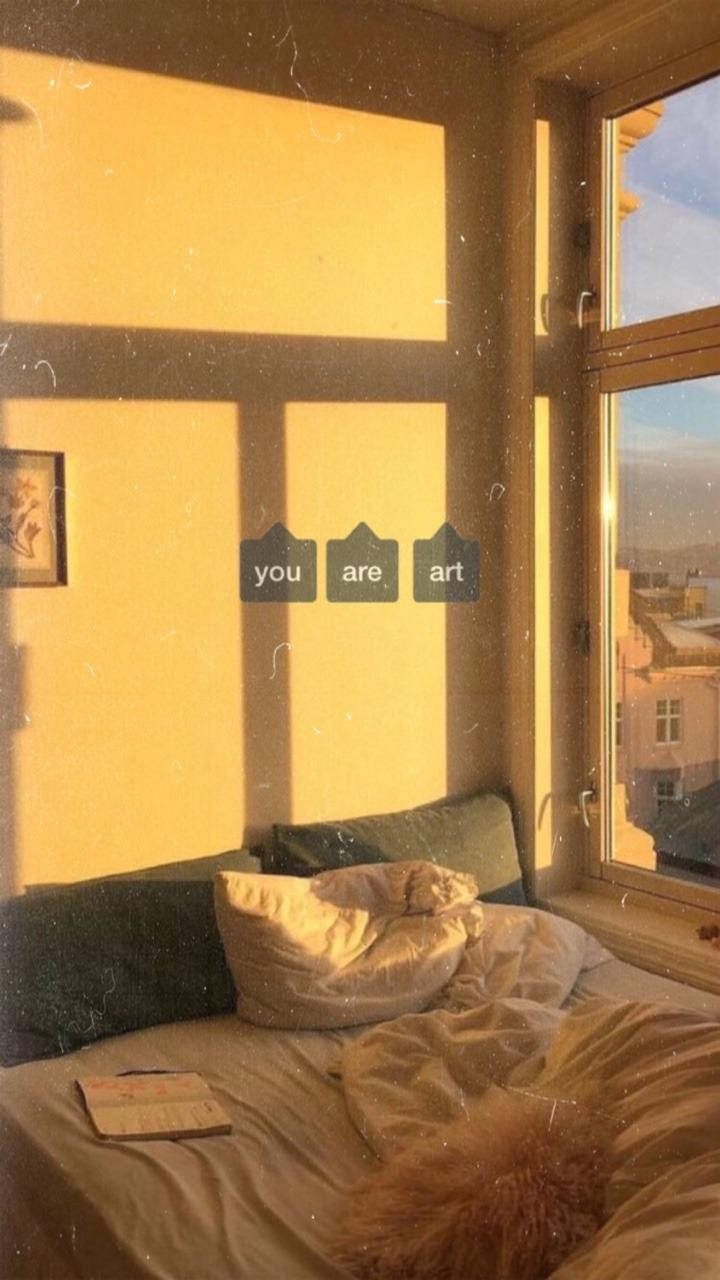 Aesthetic Home 桌布 壁紙 — 陽光穿過窗戶，將溫暖的金色光線灑在一張舒適的床上，床上放著枕頭和一條毛絨絨的毯子。