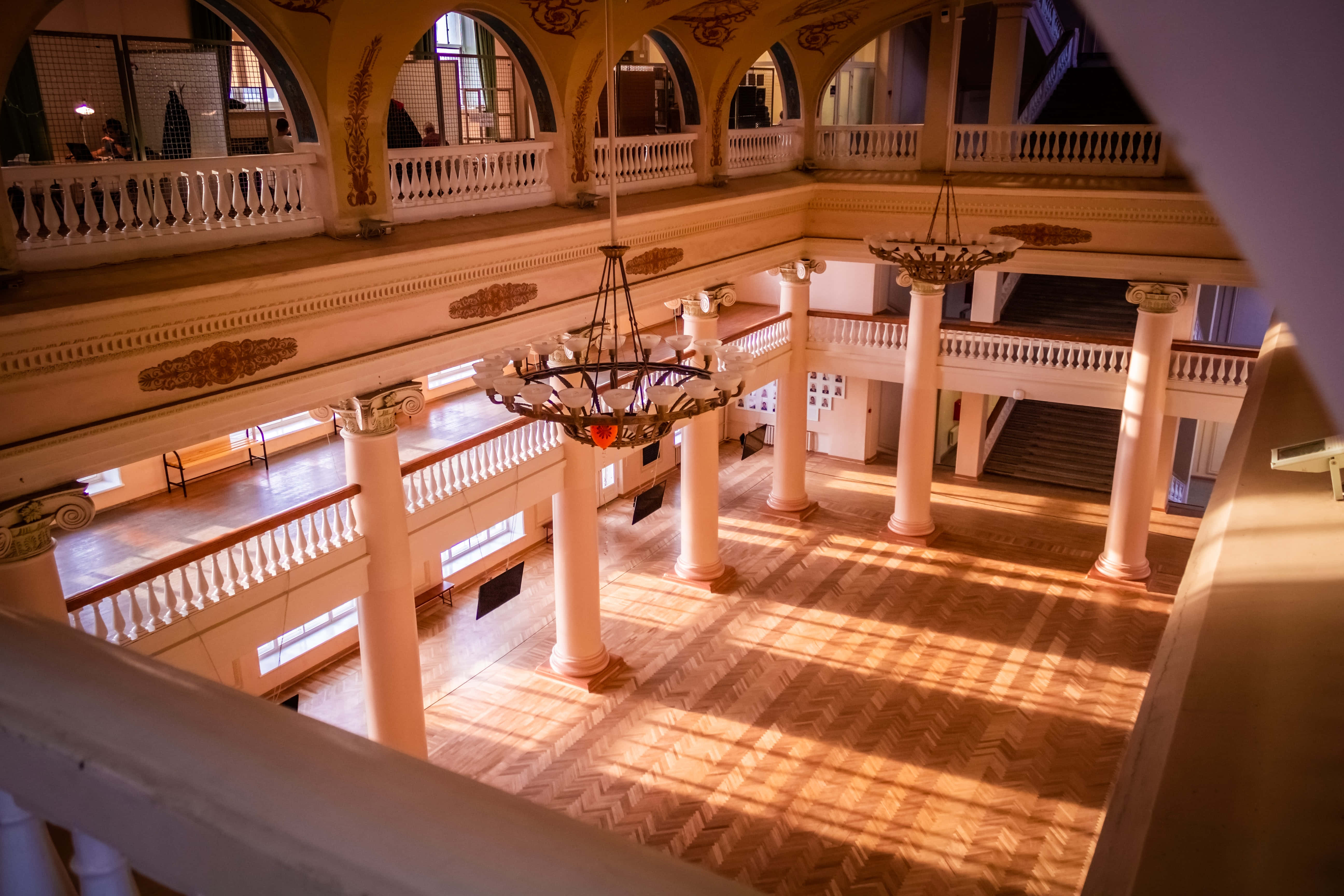 Ballroom 桌布 壁紙 — 陽光穿過窗戶，照亮了一個宏偉的多層中庭，內有華麗的柱子和吊燈。