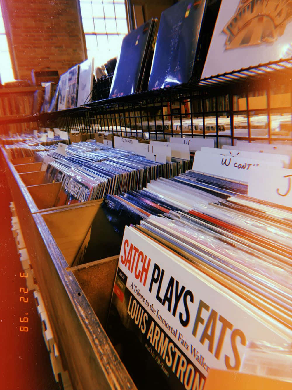 90's Vintage Retro Aesthetic 桌布 壁紙 — 陽光穿過窗戶，照亮了舒適唱片店裡一排排復古黑膠唱片。