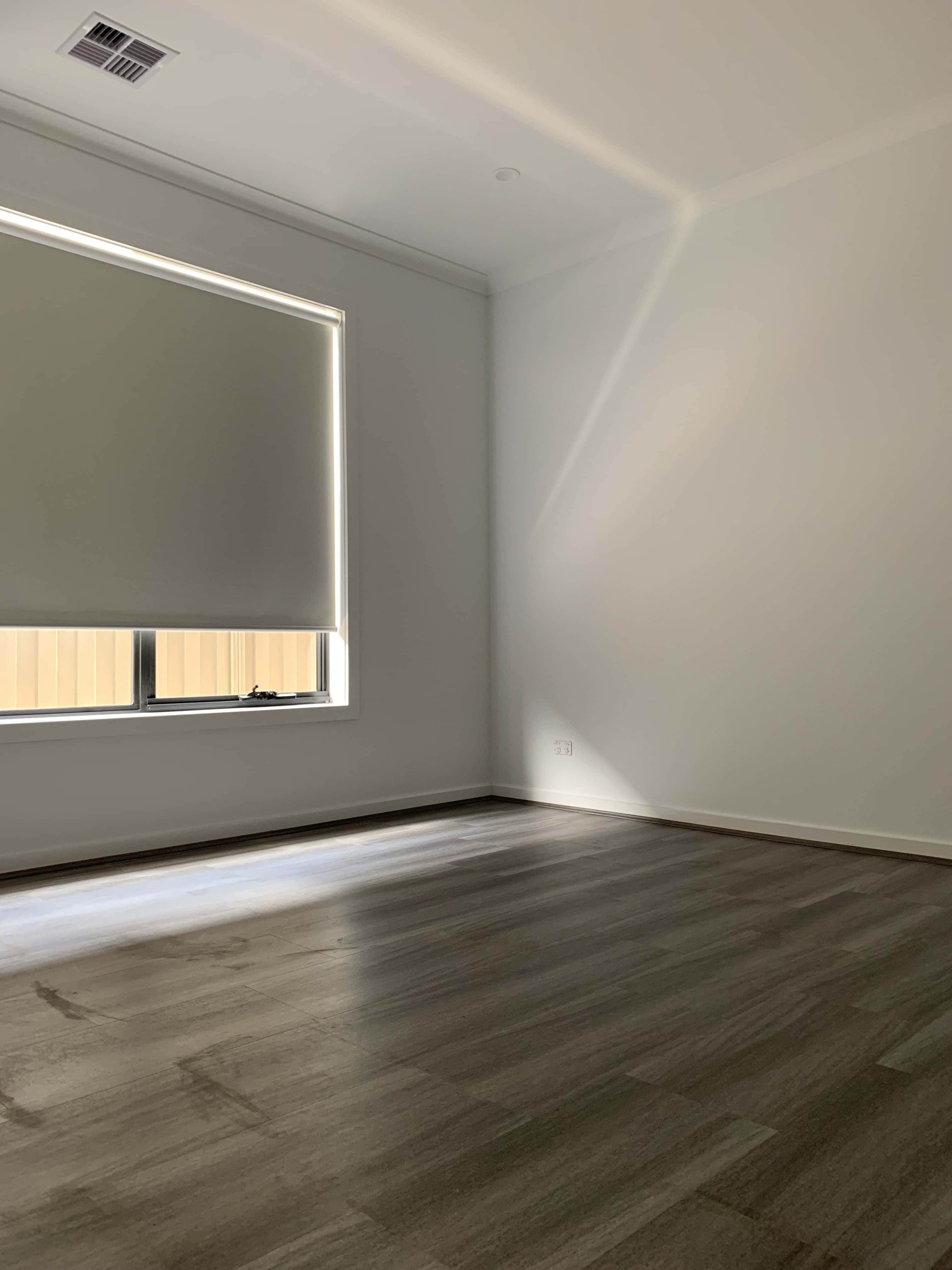 Empty Room 桌布 壁紙 — 陽光穿過窗戶，窗簾部分拉下，照在空無一物的極簡房間的裸露木地板上。