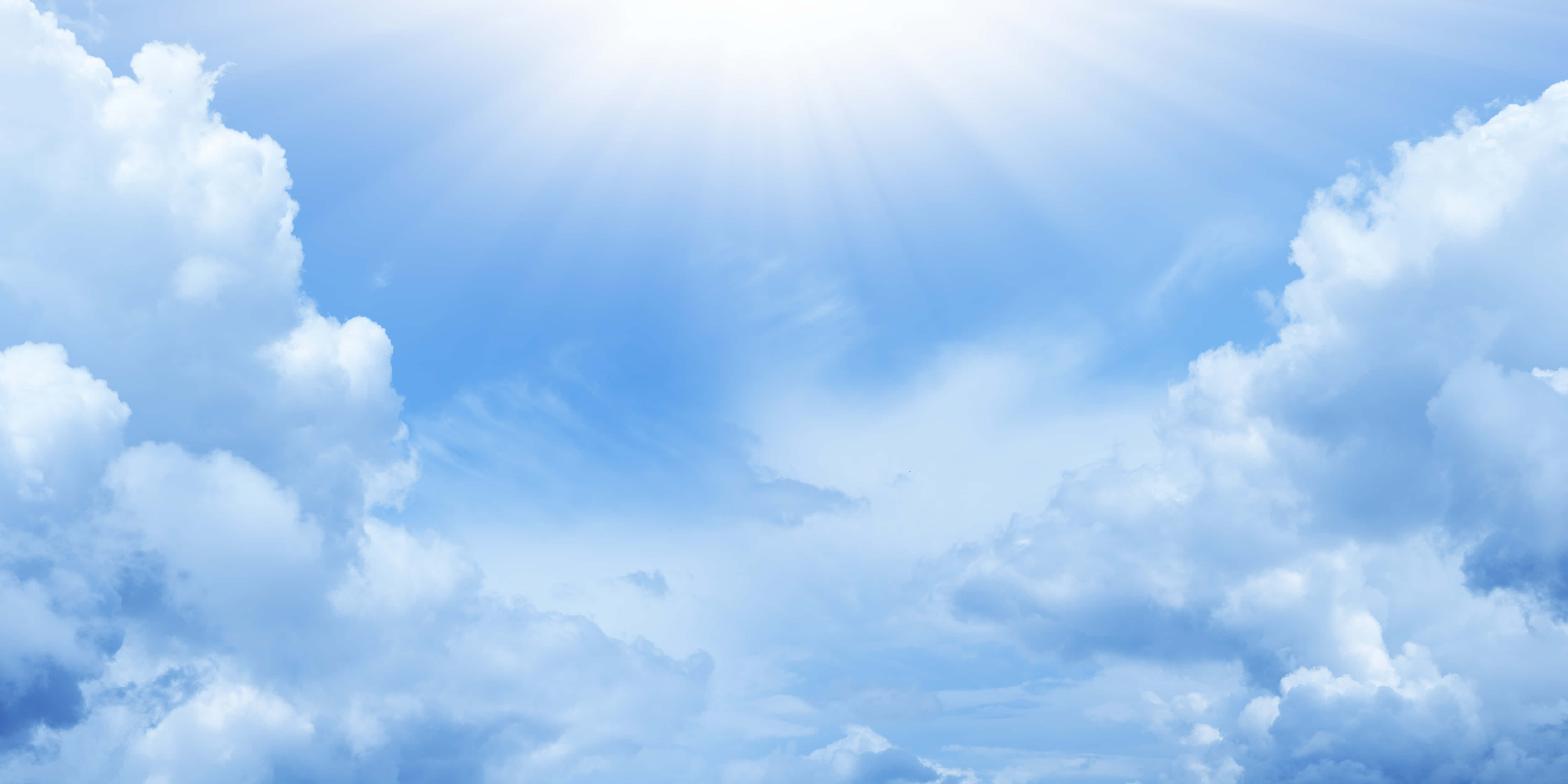 Blue Sky 桌布 壁紙 — 陽光穿過蓬鬆的白雲，在充滿活力的藍天中輻射開來。