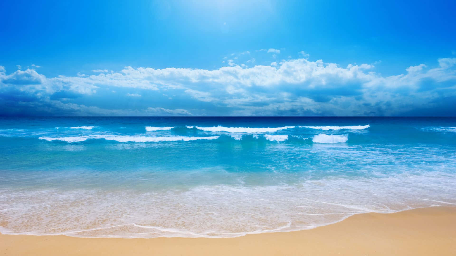 平靜 桌布 壁紙 — 陽光穿過雲層，照耀在碧綠色的海浪上，海浪拍打著金色的沙灘。