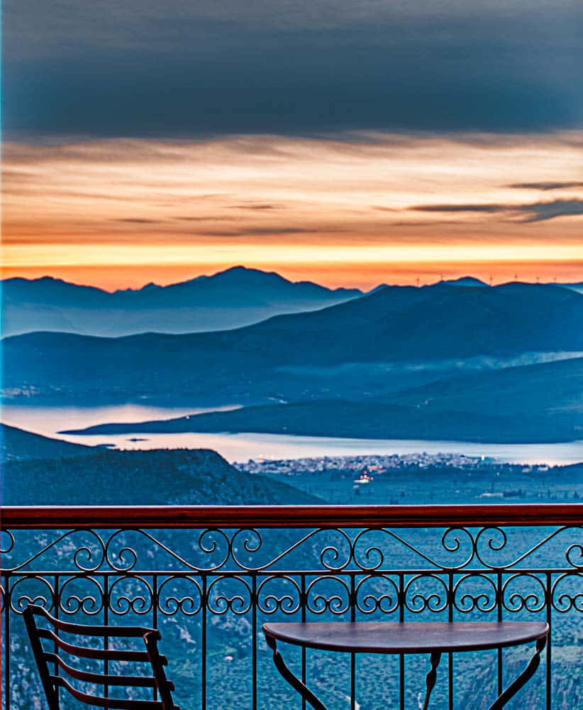 Sunset iPhone 桌布 壁紙 — 陽台俯瞰日落時分的山巒景觀，橙色天空與藍色陰影。
