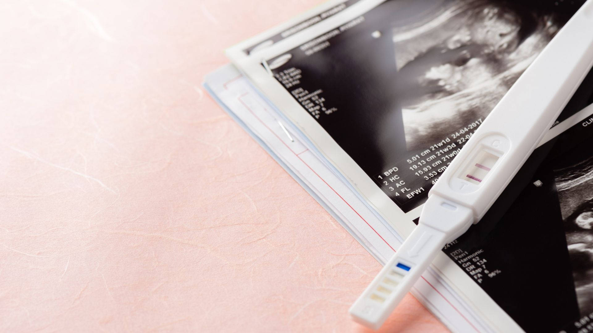 Pregnant 桌布 壁紙 — 陽性懷孕測試棒放在柔軟粉紅色表面的超音波圖像上。