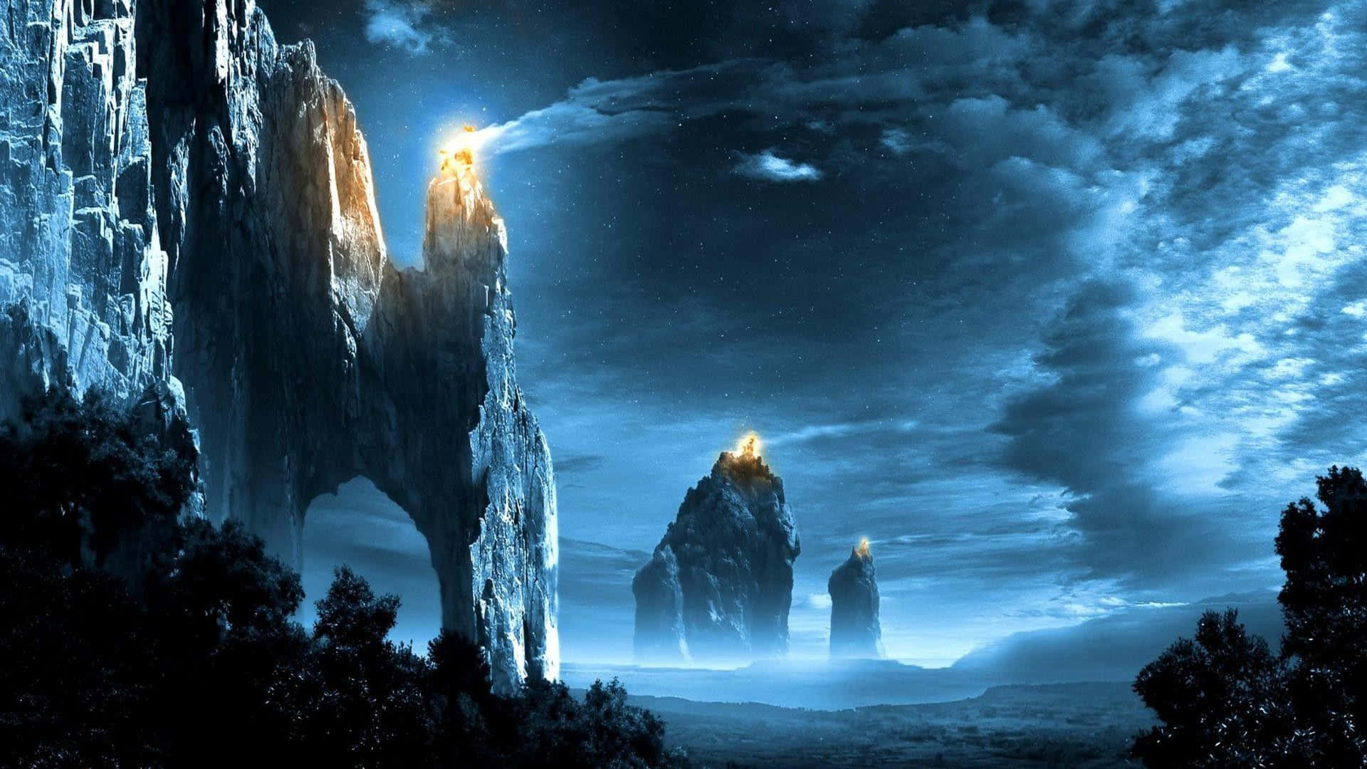 魔戒 桌布 壁紙 — 雄偉的岩石尖塔刺穿繁星點點的夜空，發光的山峰在霧氣瀰漫的山谷上投射出空靈的藍光。