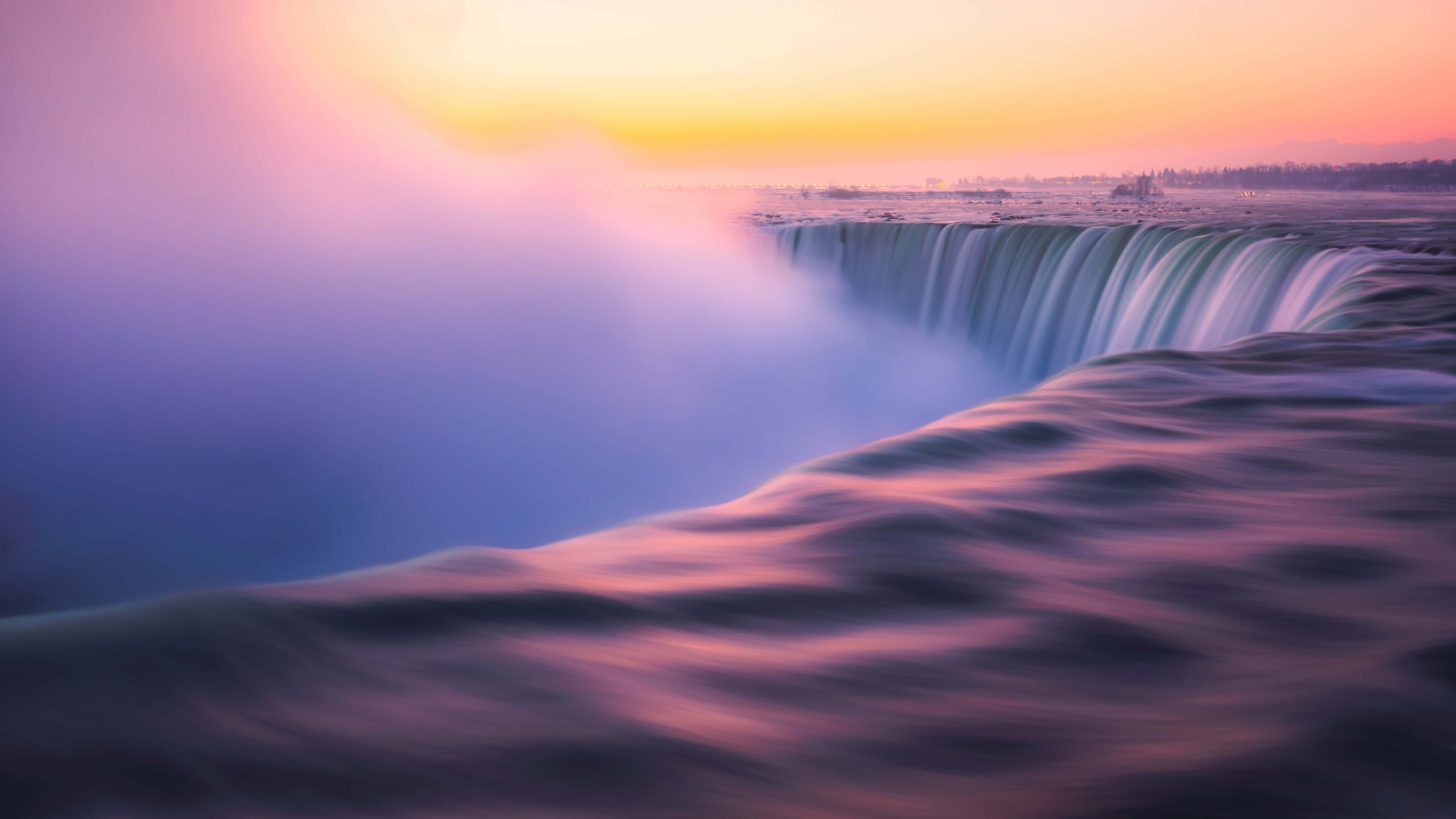 Niagara Falls 桌布 壁紙 — 雄偉的瀑布傾瀉而下，落入一個籠罩在柔和粉紅色和橙色日出色調中的霧氣池中。