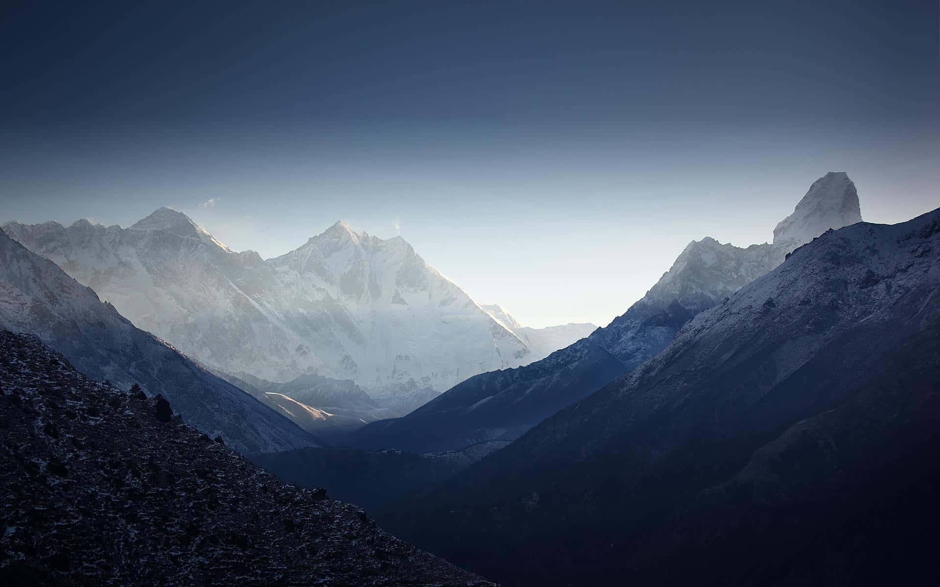 Himalaya 桌布 壁紙 — 雄偉的雪山山脈沐浴在柔和的黎明光線中，山谷裡有深藍色的陰影。
