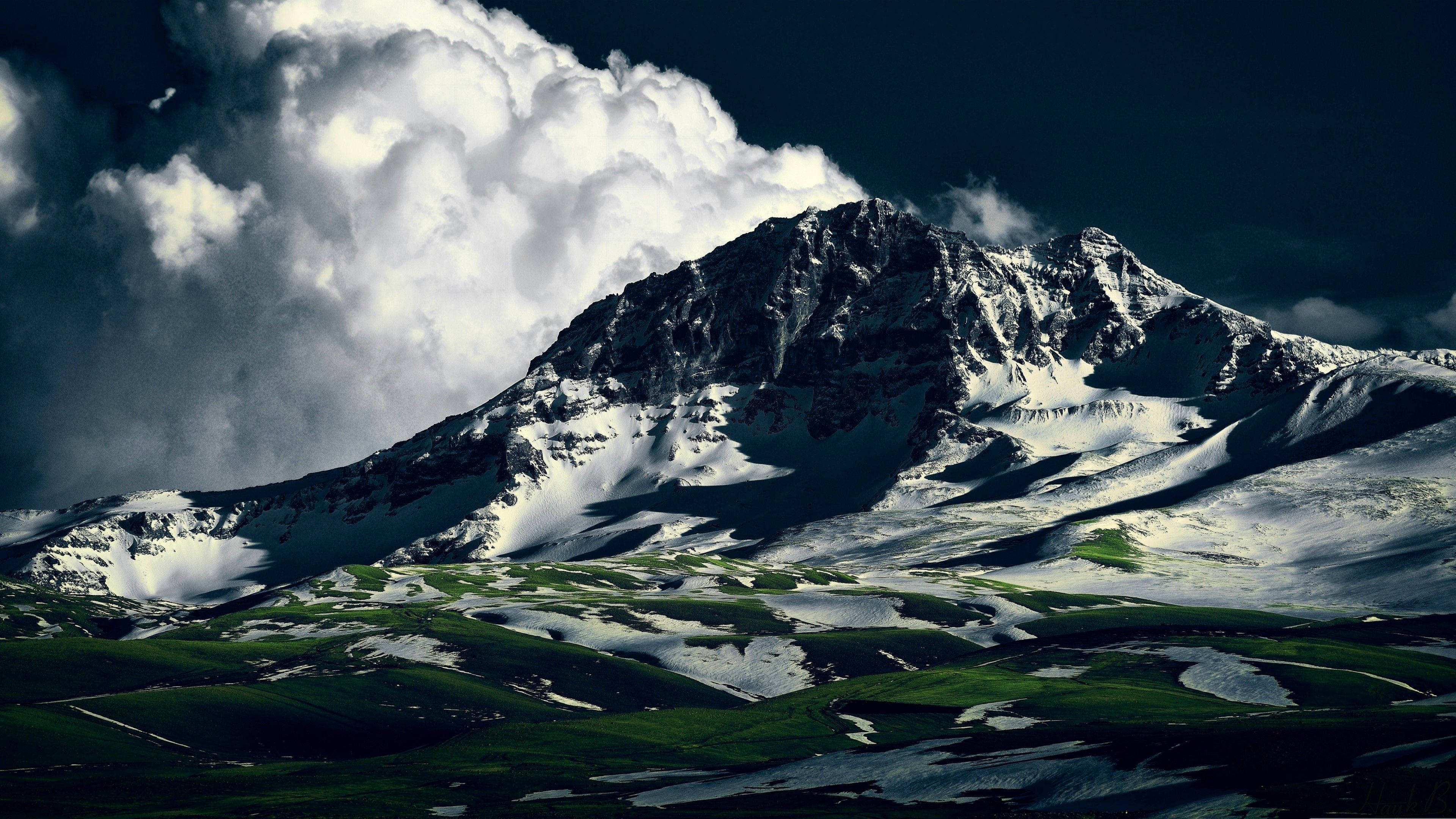 Armenia 桌布 壁紙 — 雄偉的雪山峰在戲劇性的風暴雲下升起，下方是翠綠的山谷。