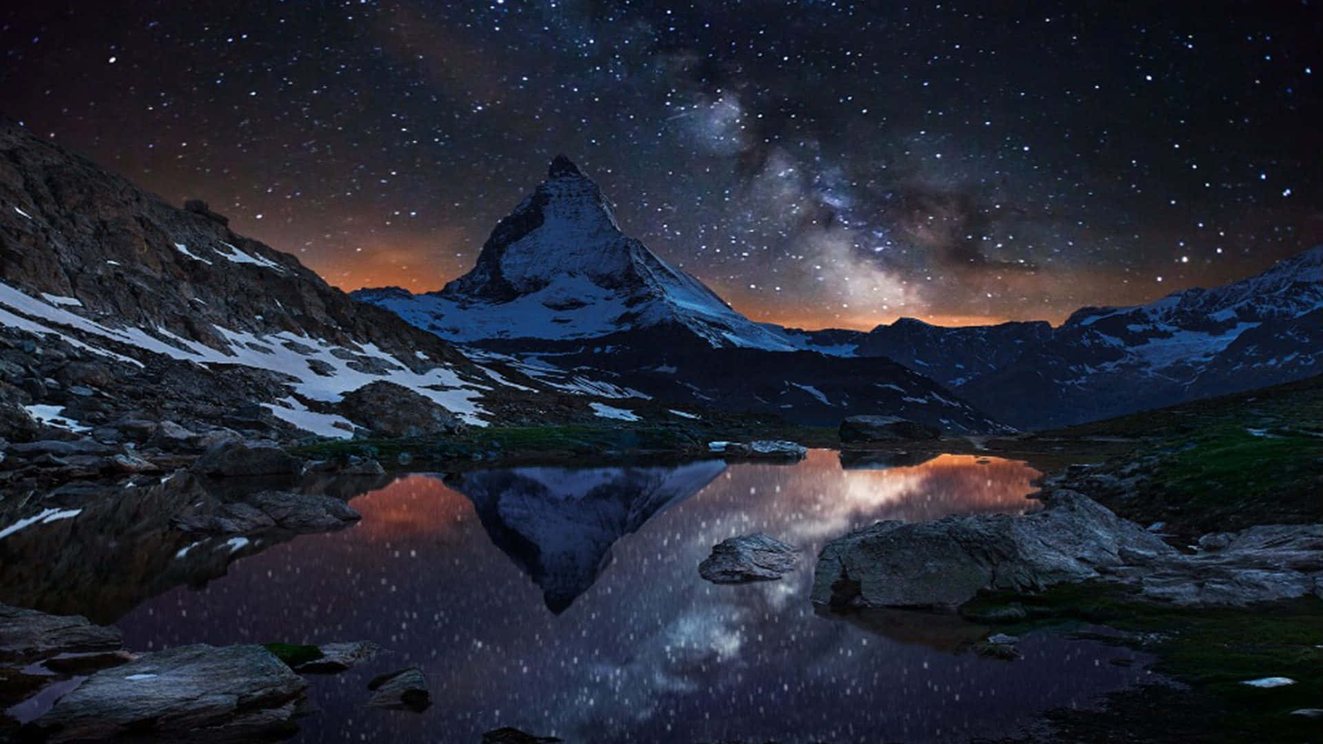 銀河 桌布 壁紙 — 雄偉的雪山峰頂，在繁星點點的夜空下，銀河倒映在寧靜的高山湖泊中。