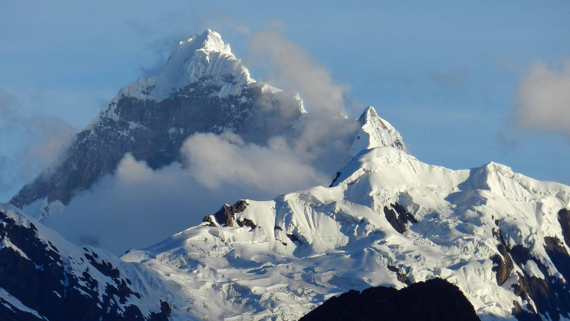 Peru 桌布 壁紙 — 雄偉的雪山峰頂在清澈的藍天下穿透縷縷雲霧。