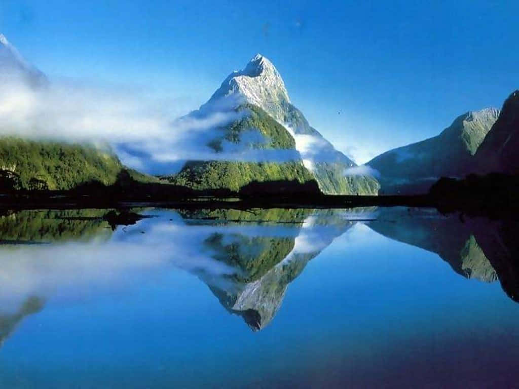 山景 桌布 壁紙 — 雄偉的雪山峰頂在清澈藍天下，透過薄霧窺視著如鏡的湖面，完美倒映其中。