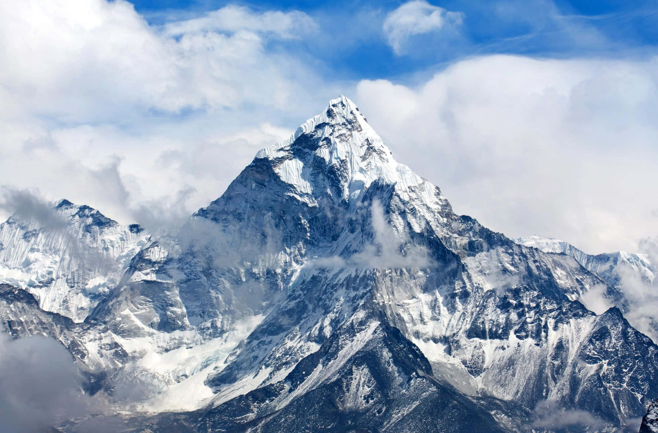 Mount Everest 桌布 壁紙 — 雄偉的雪山峰頂在湛藍天空下刺穿戲劇性的雲層。