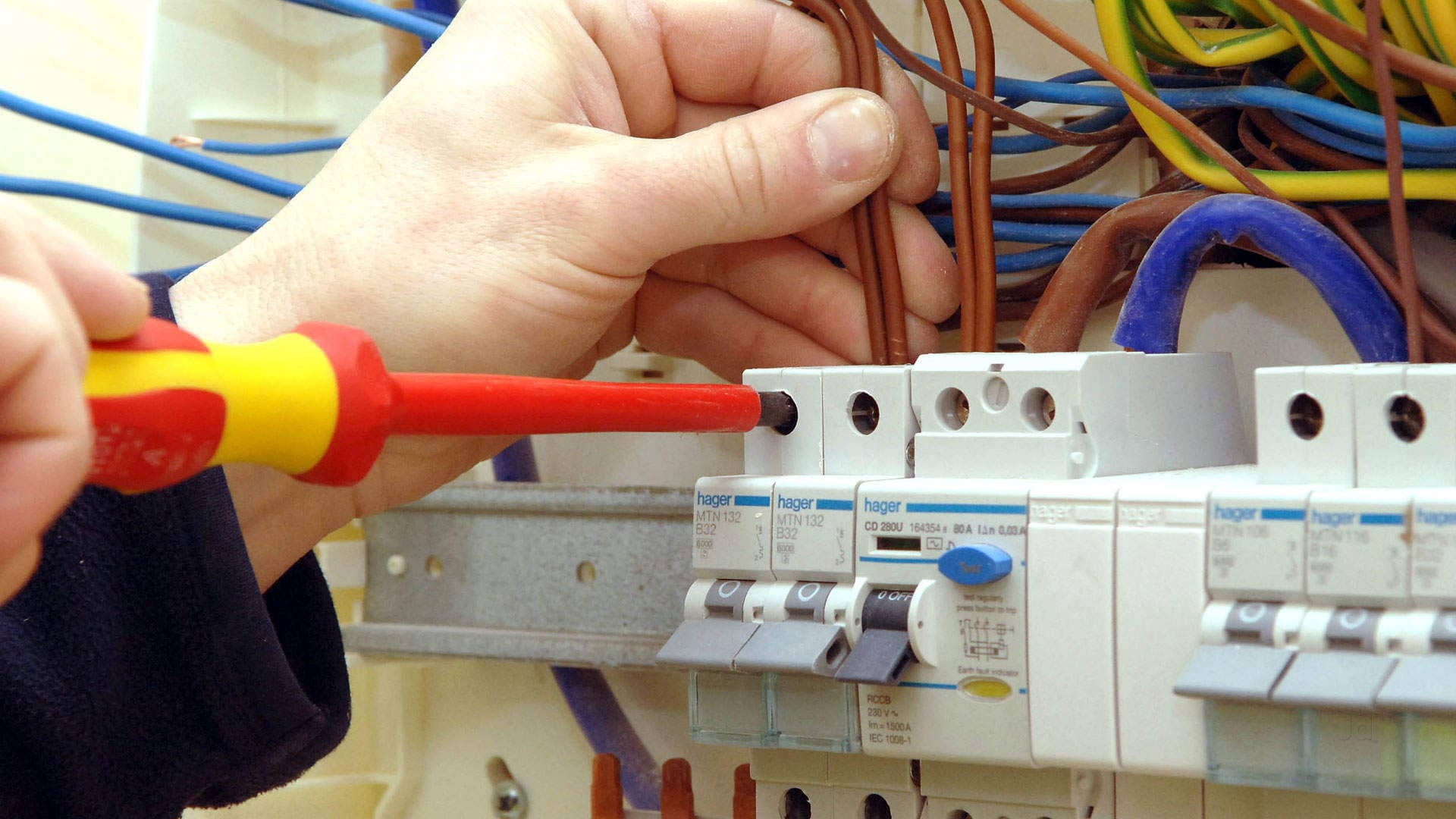 job 桌布 壁紙 — 雙手使用紅黃色螺絲起子將電線連接到白色電路斷路器面板的特寫。