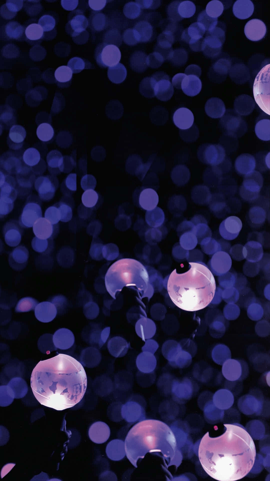 Bts Army Bomb 桌布 壁紙 — 雙手在充滿柔和紫色散景燈光的黑暗背景中，握著發光的粉紅色螢光棒。