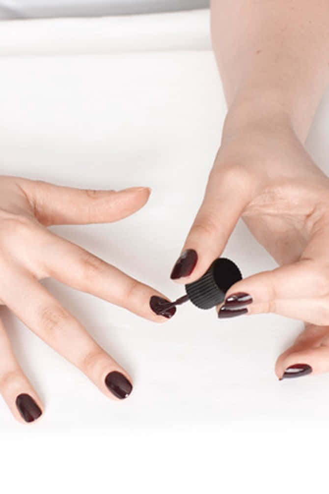 Manicure 桌布 壁紙 — 雙手在白色表面上塗抹光面深紅色指甲油的近距離特寫。